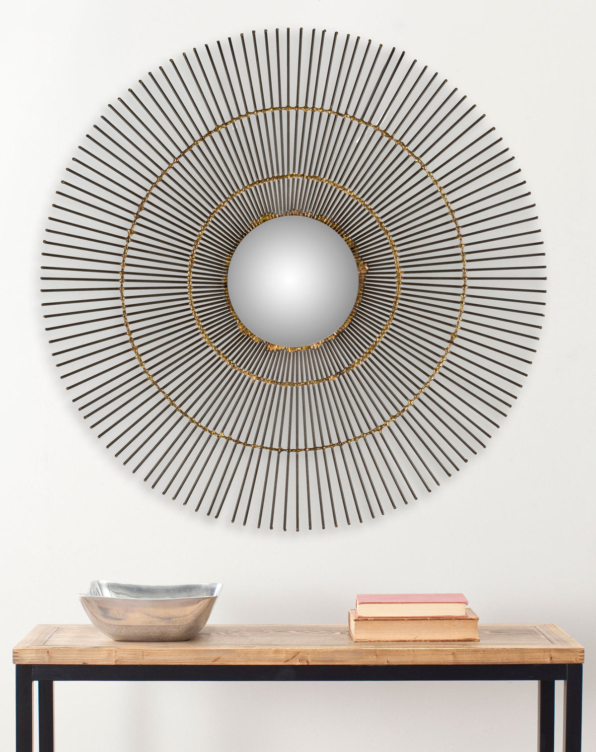 Slender sunburst spokes and concentric gold rings give this round wall mirror sculptural appeal.