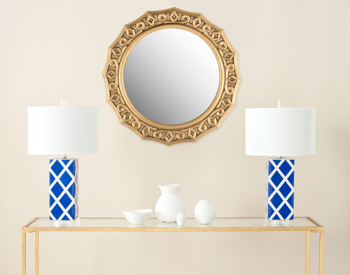 Ornate gold wall mirror adds warmth above a console with its round glass and carved frame