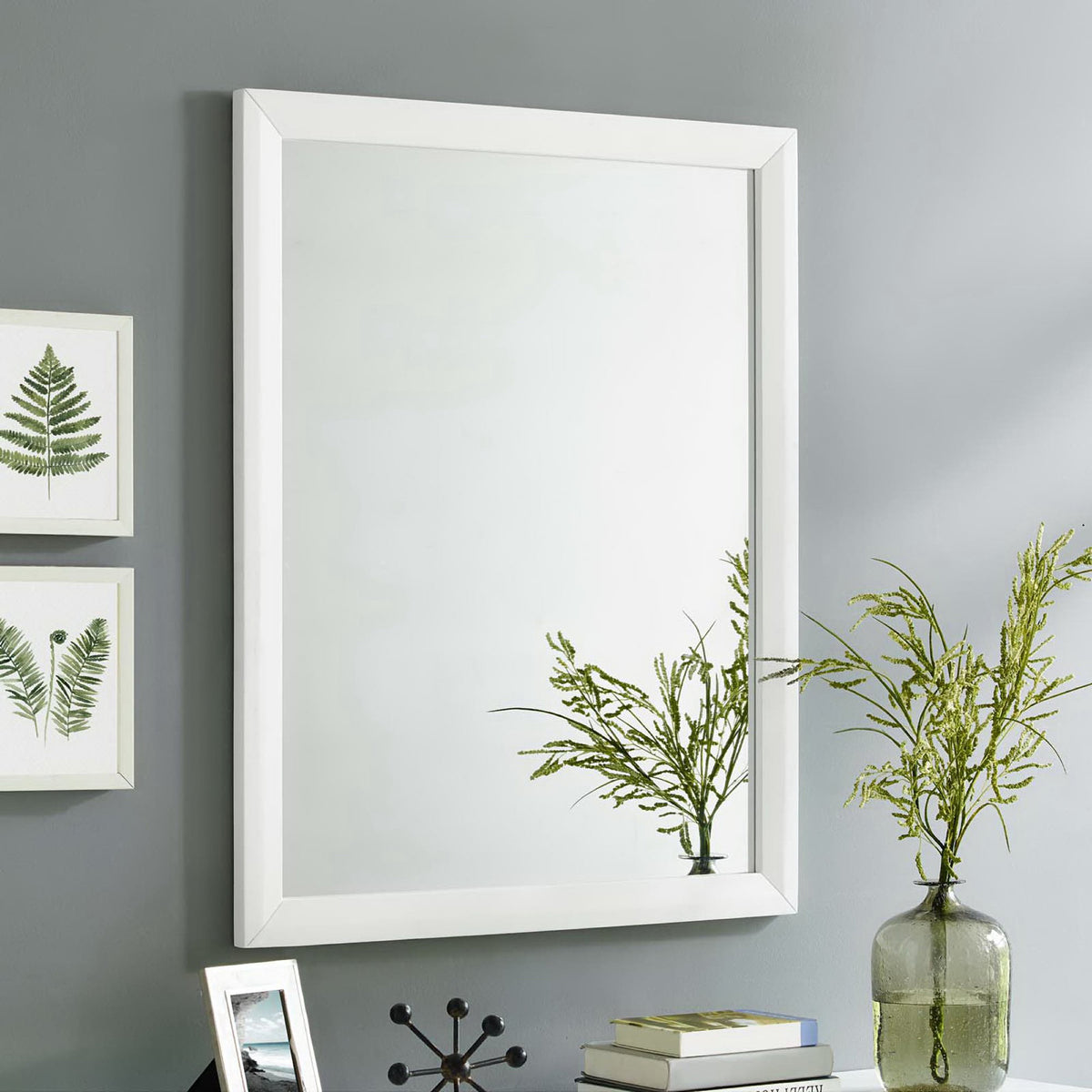 A white rectangular mirror brings a crisp focal point to a gray wall and leafy vignette