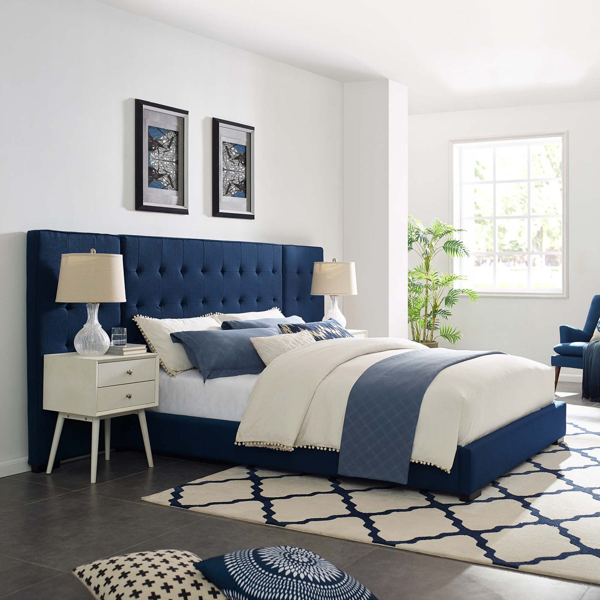 A broad, tufted azure blue headboard anchors the softly upholstered platform bed.