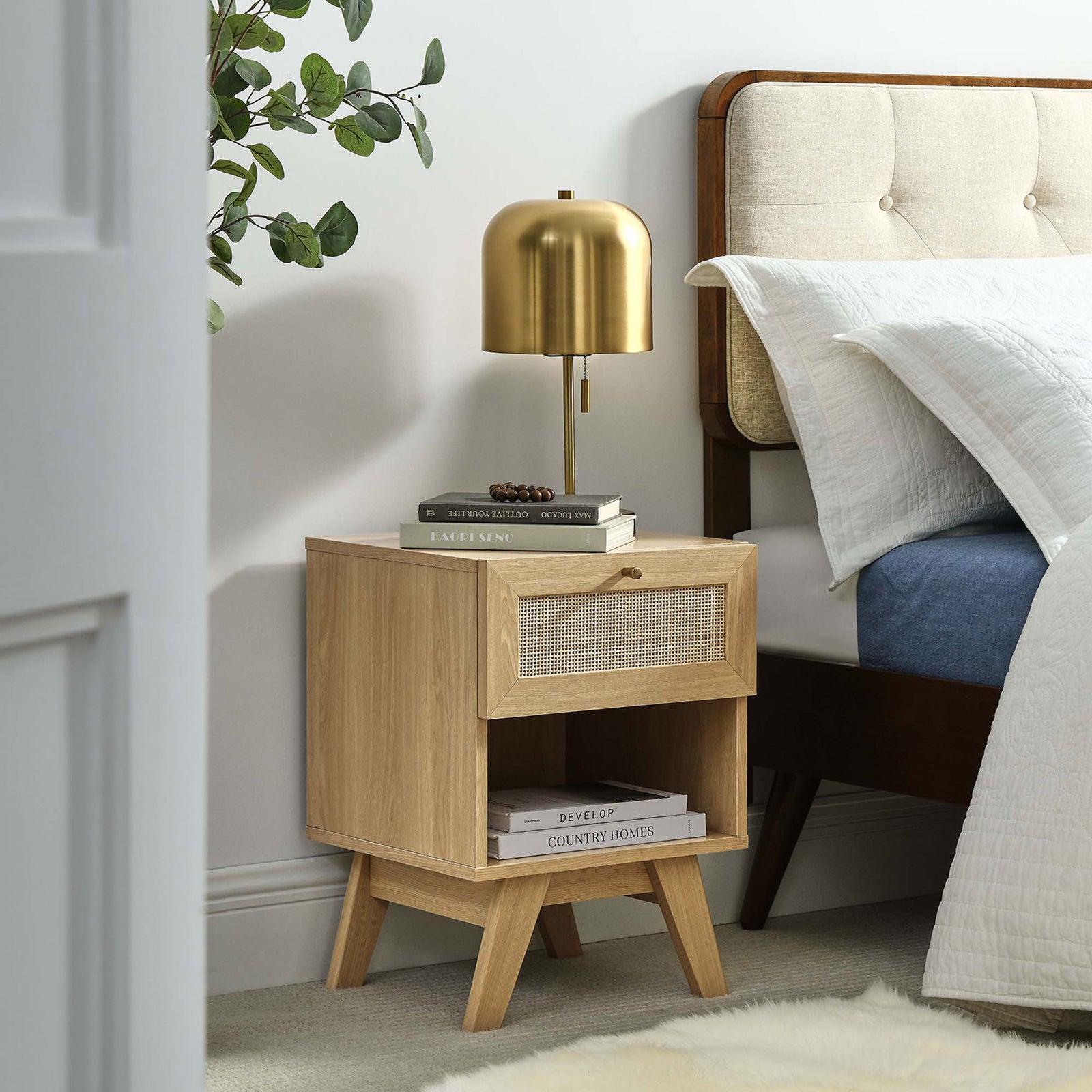Soma oak nightstand styled beside a bed with books and lamp, showcasing rattan drawer and open storage shelf || MOD-7049-OAK || front_angle_room