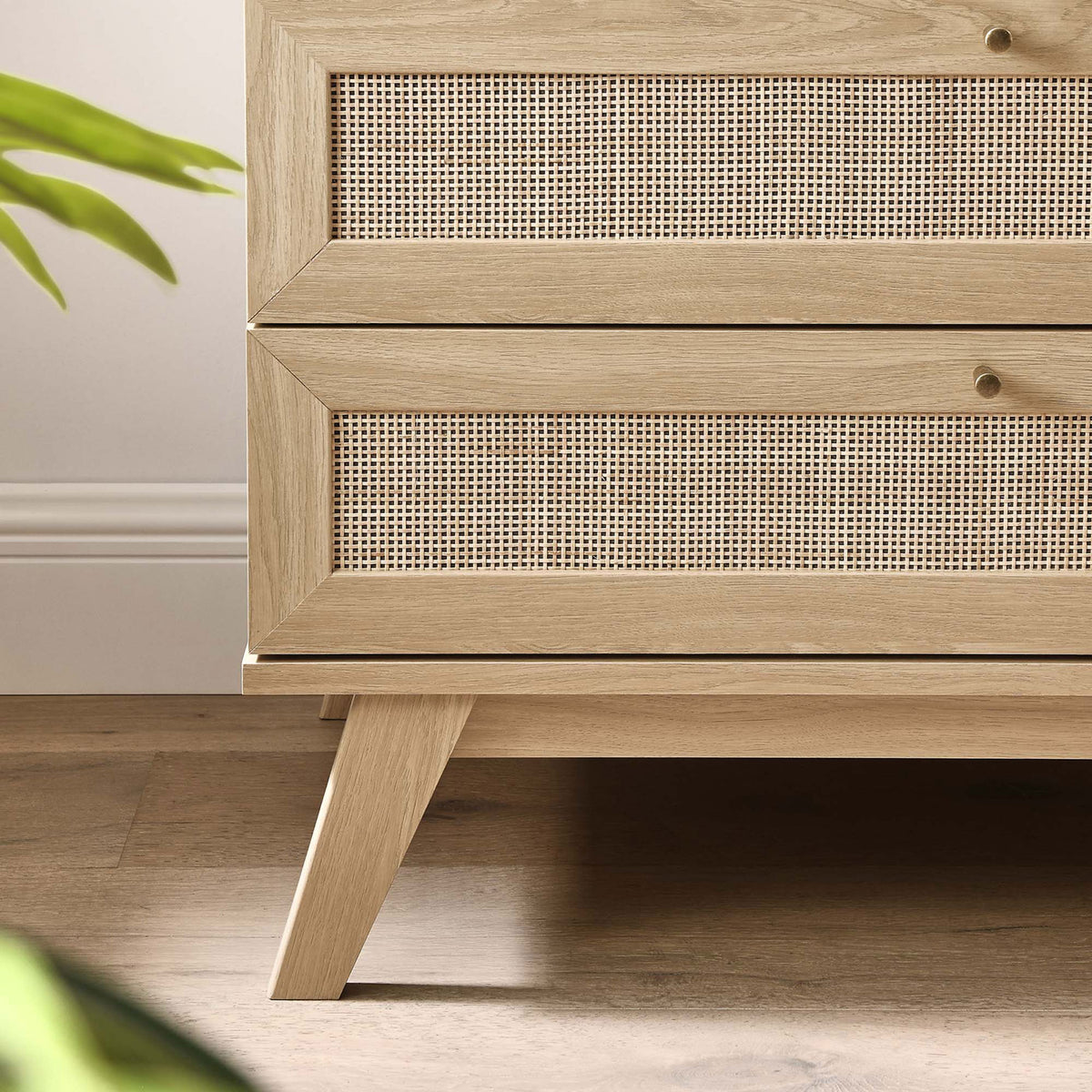 Lower corner of oak dresser showing angled leg and rattan drawer front over warm wood floor || MOD-7051-OAK || leg_room