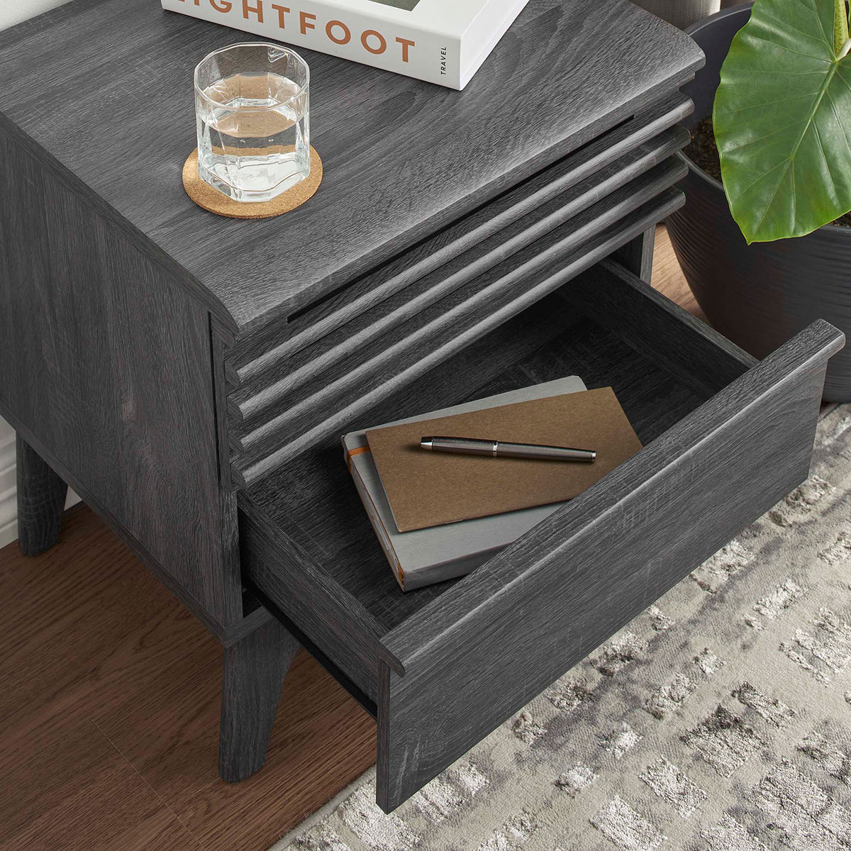 Charcoal nightstand drawer neatly organizing notebooks and decor beside a glass of water and leafy plant || MOD-7071-CHA || storage_open_room