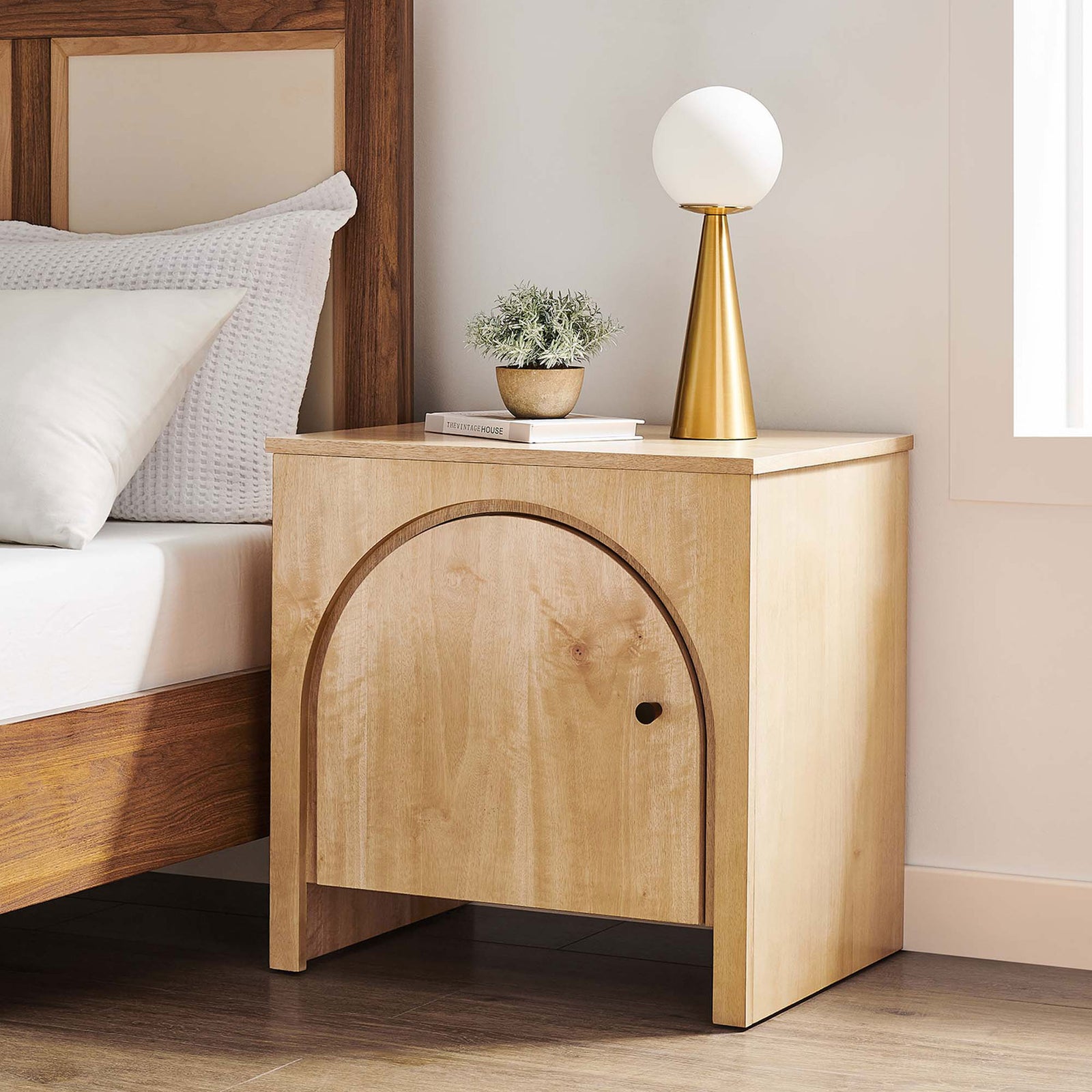 Arched oak nightstand styled by the bed with lamp and decor for a warm modern bedroom. || MOD-7109-OAK || front_angle_room