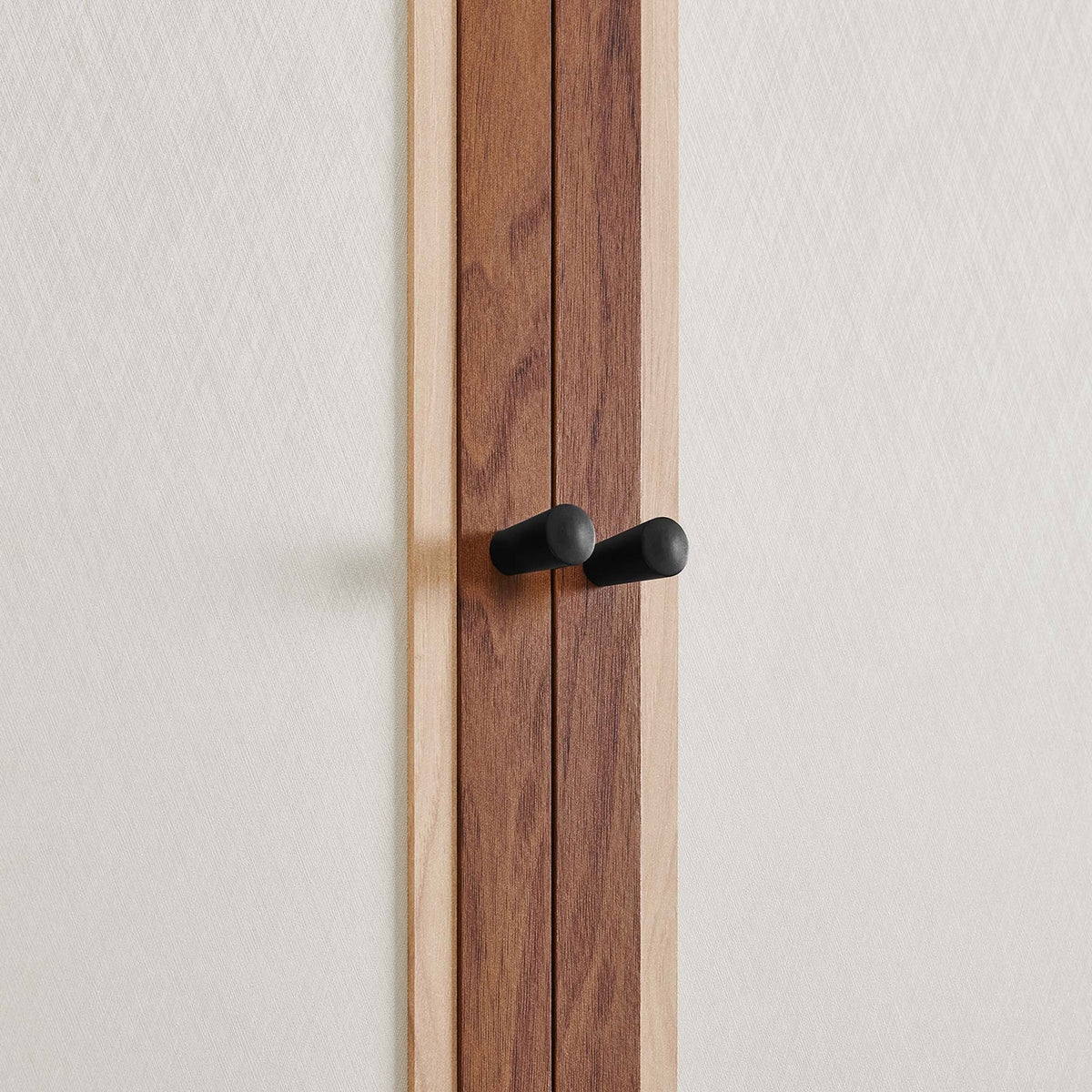 Detail of twin black knob pulls set against the soft linen-textured cabinet doors || MOD-7156-WAL || handle_studio