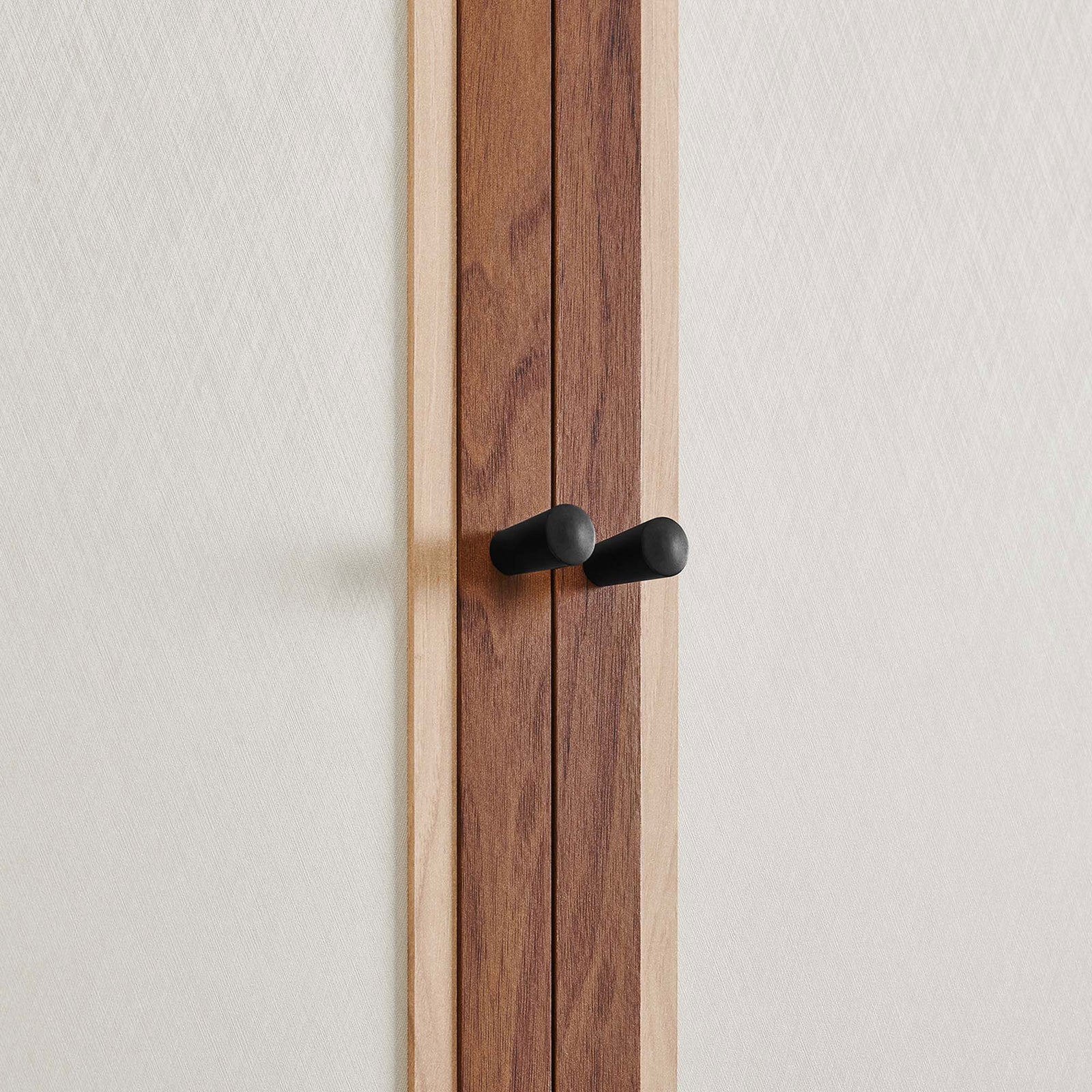 Detail of twin black knob pulls set against the soft linen-textured cabinet doors || MOD-7156-WAL || handle_studio