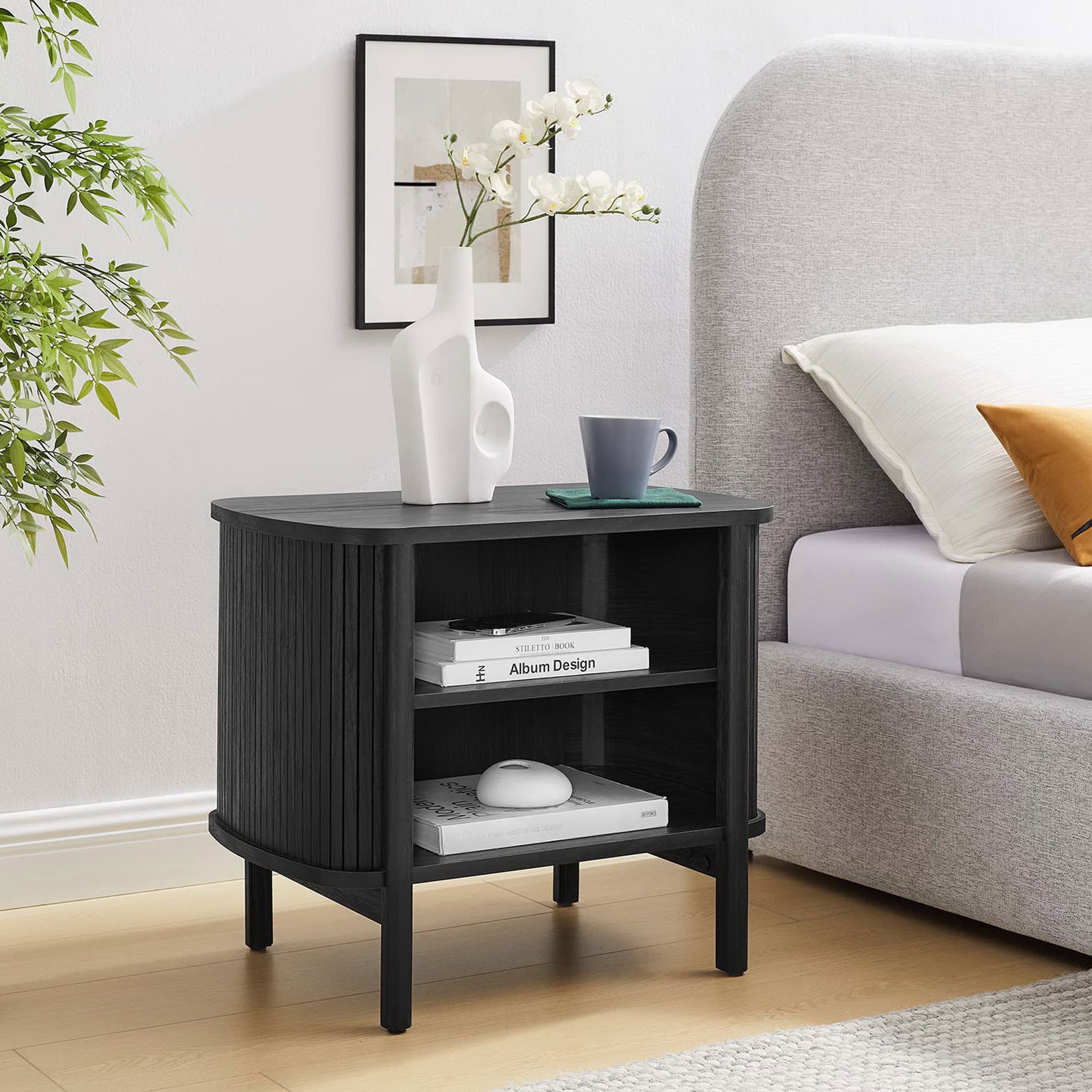 Black nightstand styled beside a bed with books and decor neatly arranged on its open shelves || MOD-7157-BLK || front_angle_room