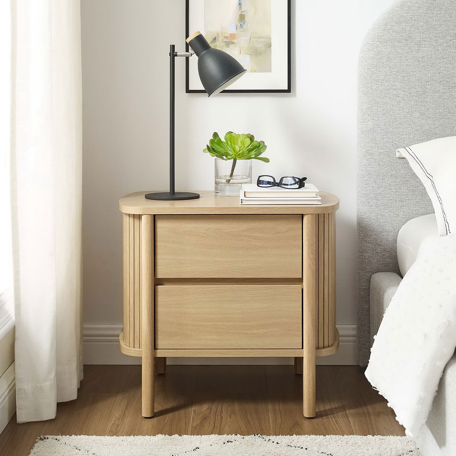 Cadence oak nightstand beside a bed, topped with a lamp and decor for a cozy modern bedroom vignette. || MOD-7158-OAK || front_room