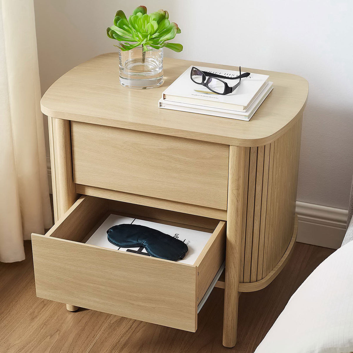 Cadence oak nightstand styled beside a bed with an open drawer for keeping nighttime essentials handy. || MOD-7158-OAK || front_angle_open_room