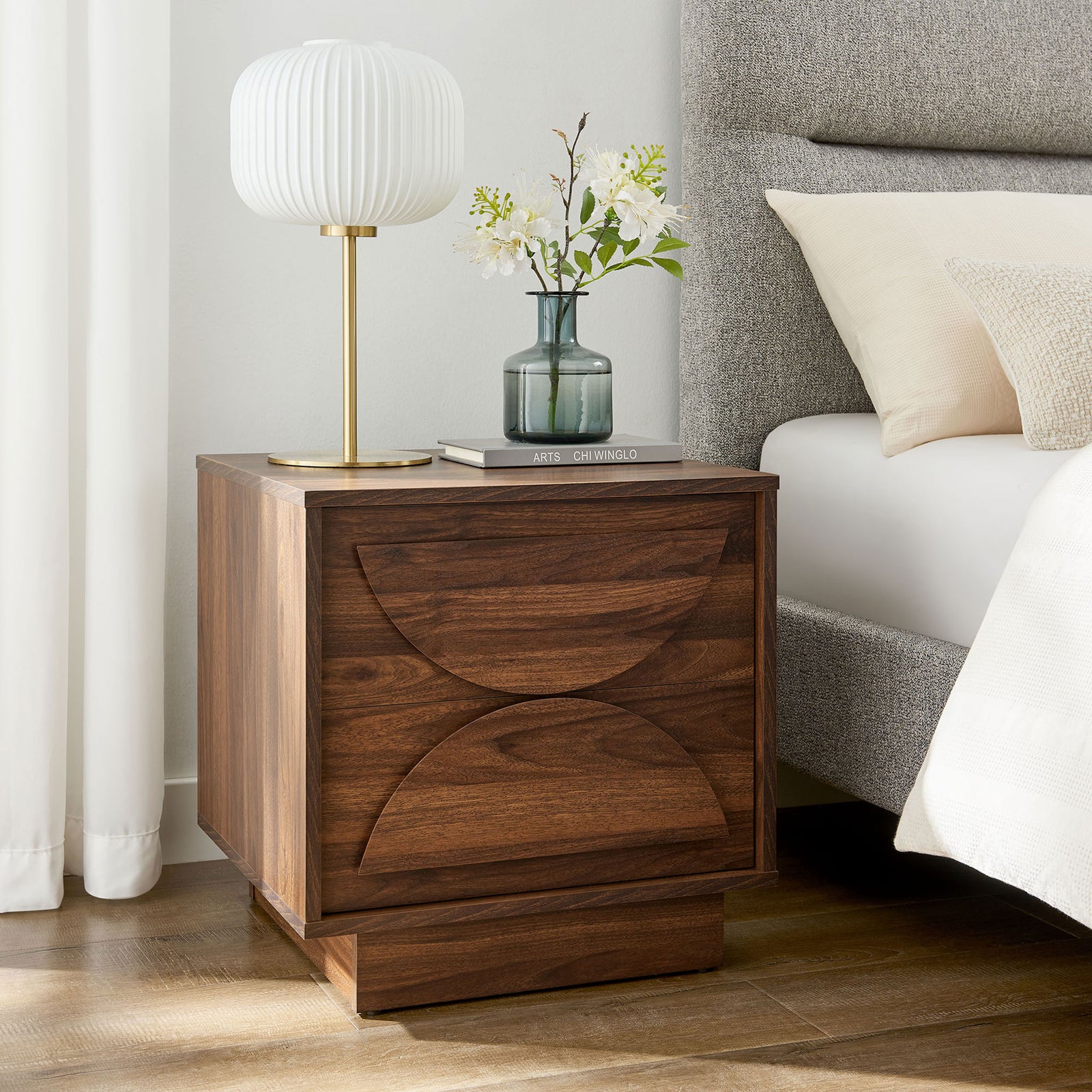 Bulwark walnut nightstand beside a bed, styled with a ribbed lamp and vase for a modern bedroom look || MOD-7162-WAL || front_angle_room