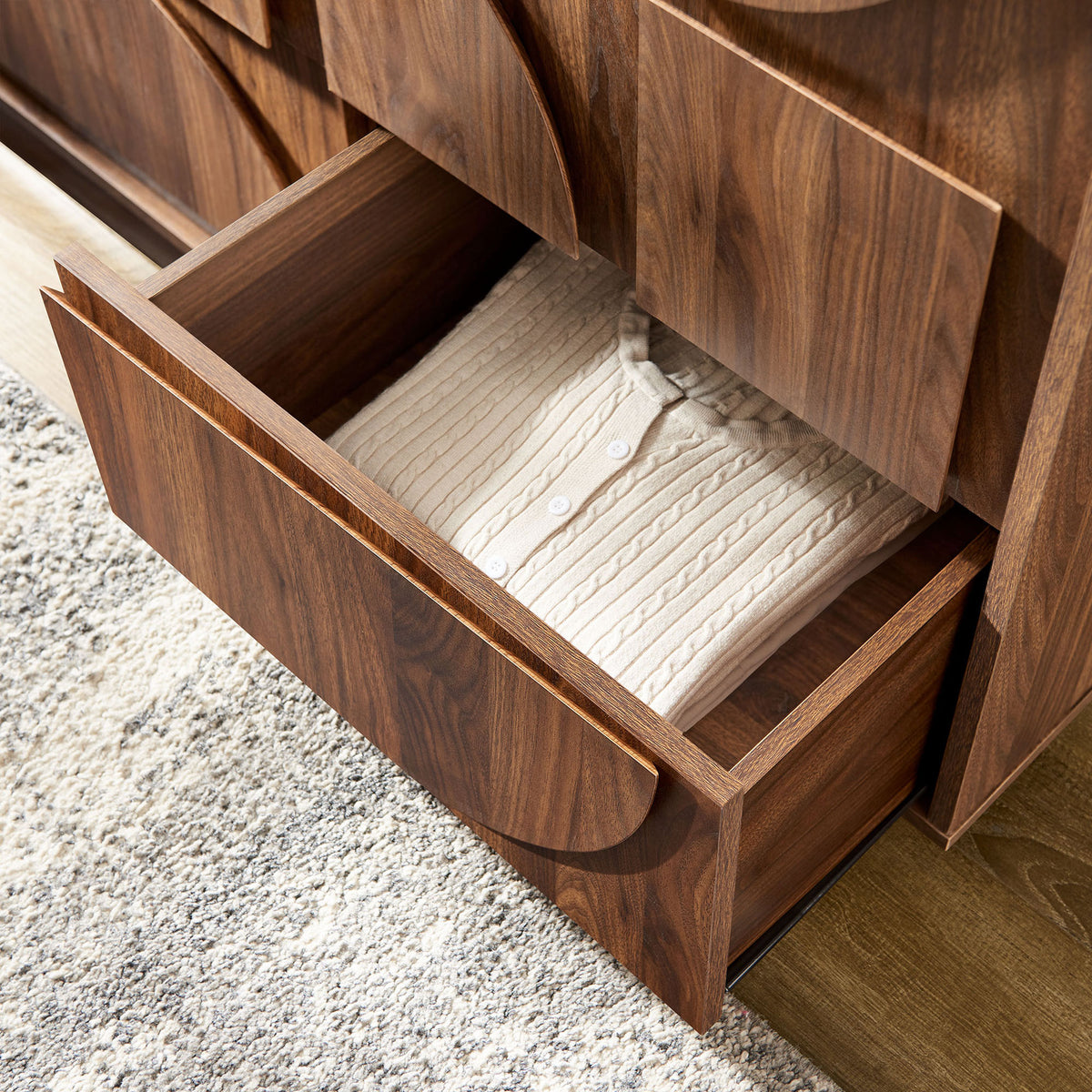 Wardrobe drawer opened in a cozy bedroom, storing a folded knit sweater above a textured rug. || MOD-7164-WAL || storage_open_room