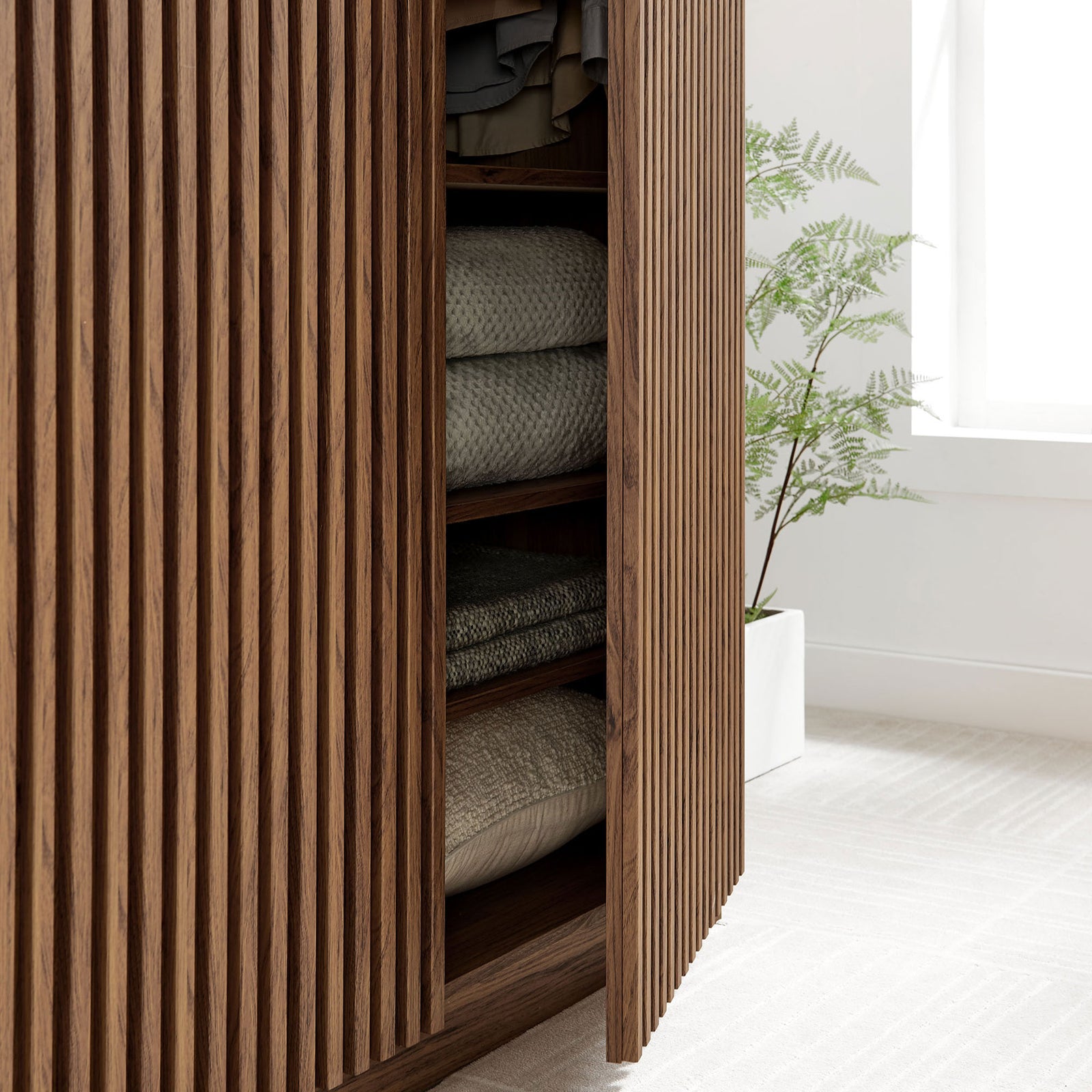Walnut wardrobe base with slatted door ajar to display folded blankets and linens on lower shelves || MOD-7182-WAL || storage_open_room