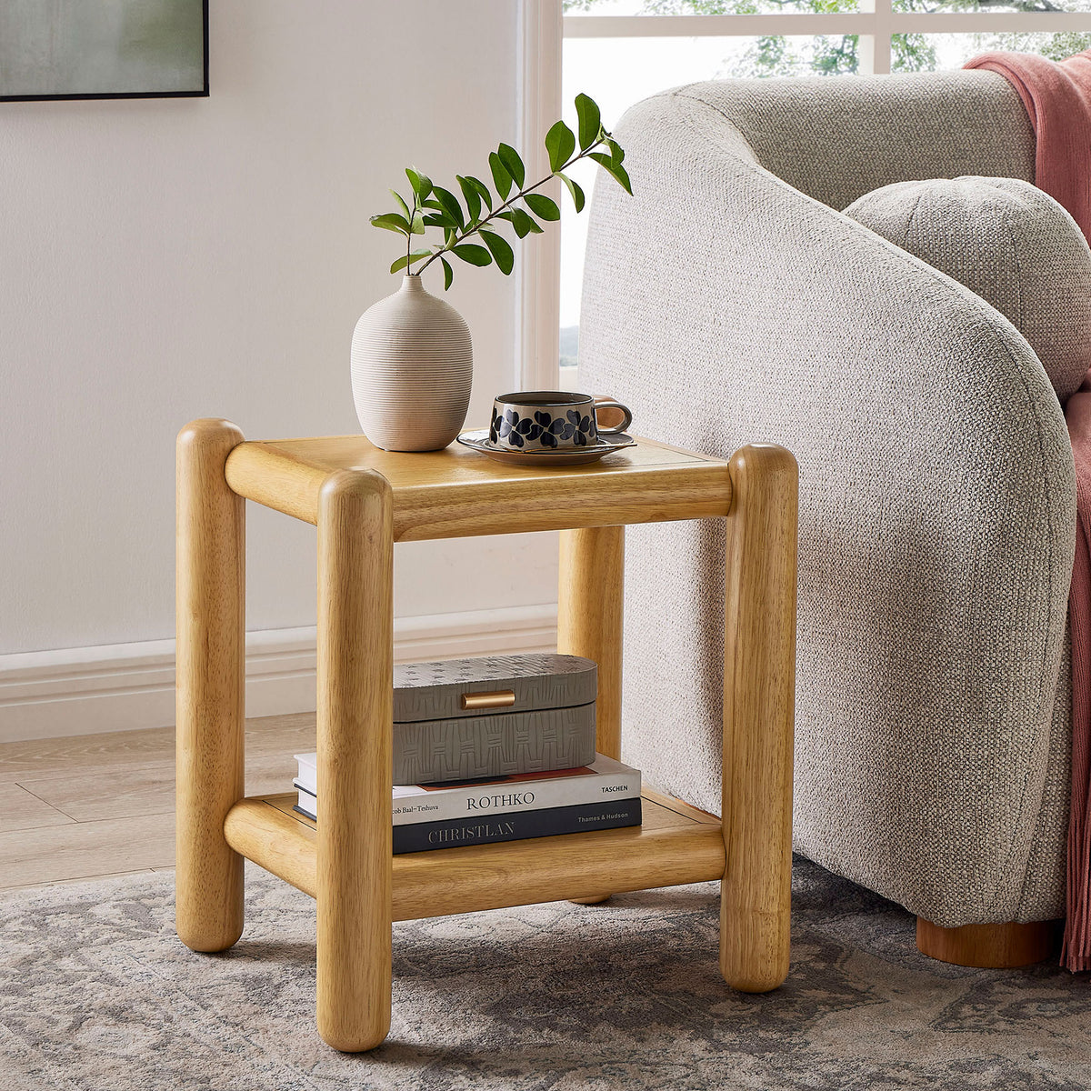 Arcus oak side table styled beside a sofa with decor on the top and books stored on the lower shelf. || MOD-7226-OAK || front_angle_room