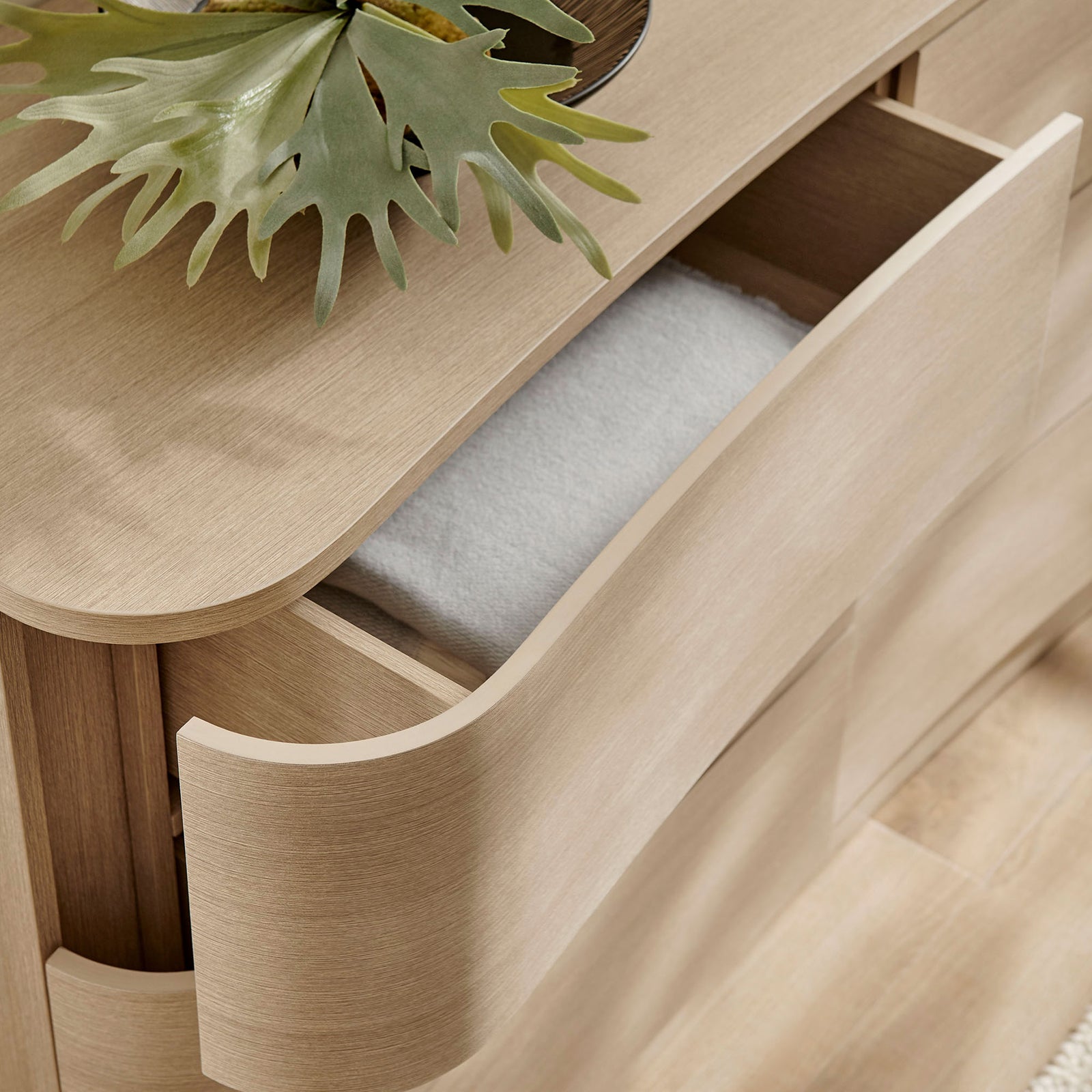 Open drawer styled with folded textiles and decor on the smooth top of the light oak dresser || MOD-7229-BOA || storage_open_room