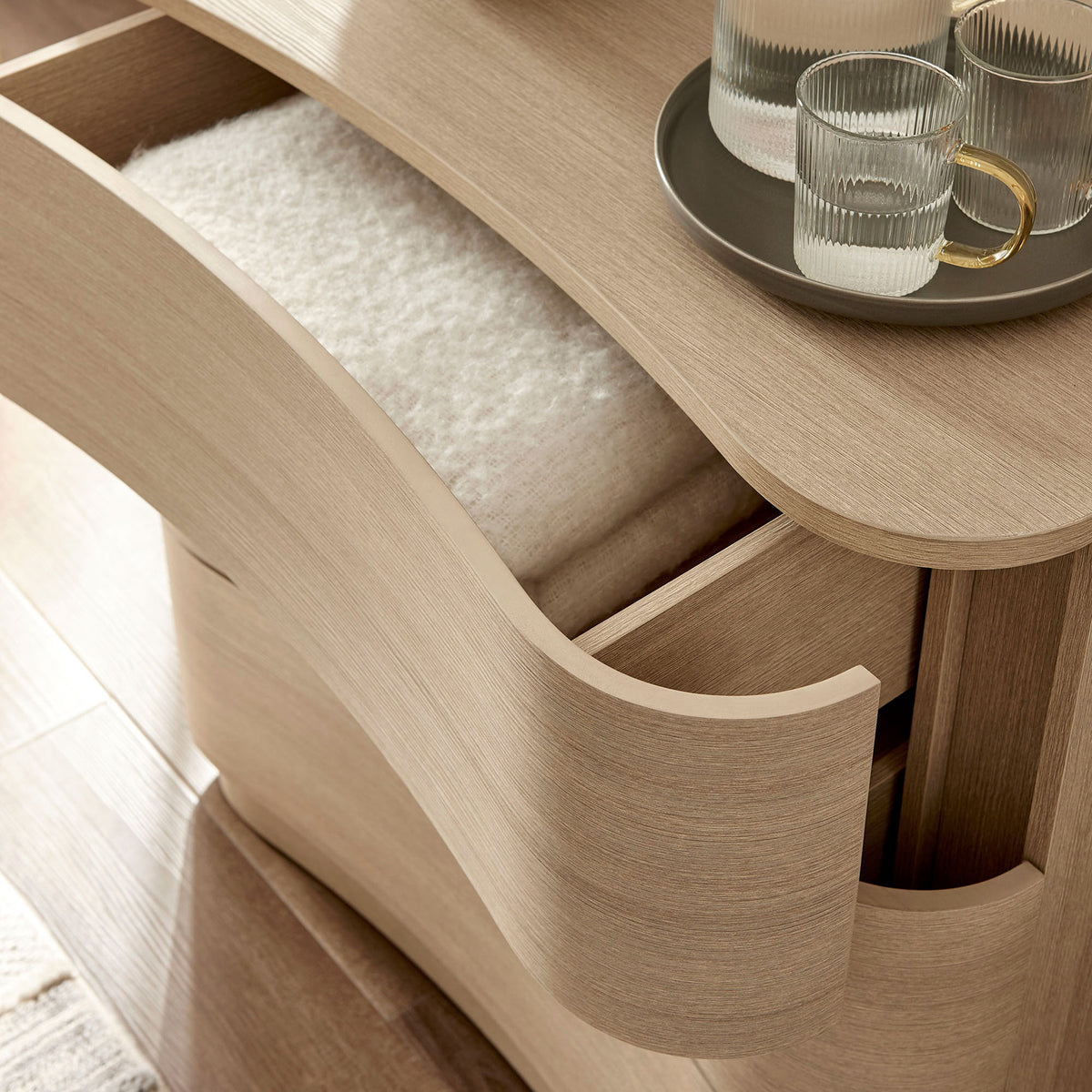 Styled top drawer holds folded textiles and glassware, showcasing everyday storage in a cozy bedroom setting || MOD-7230-BOA || storage_open_room