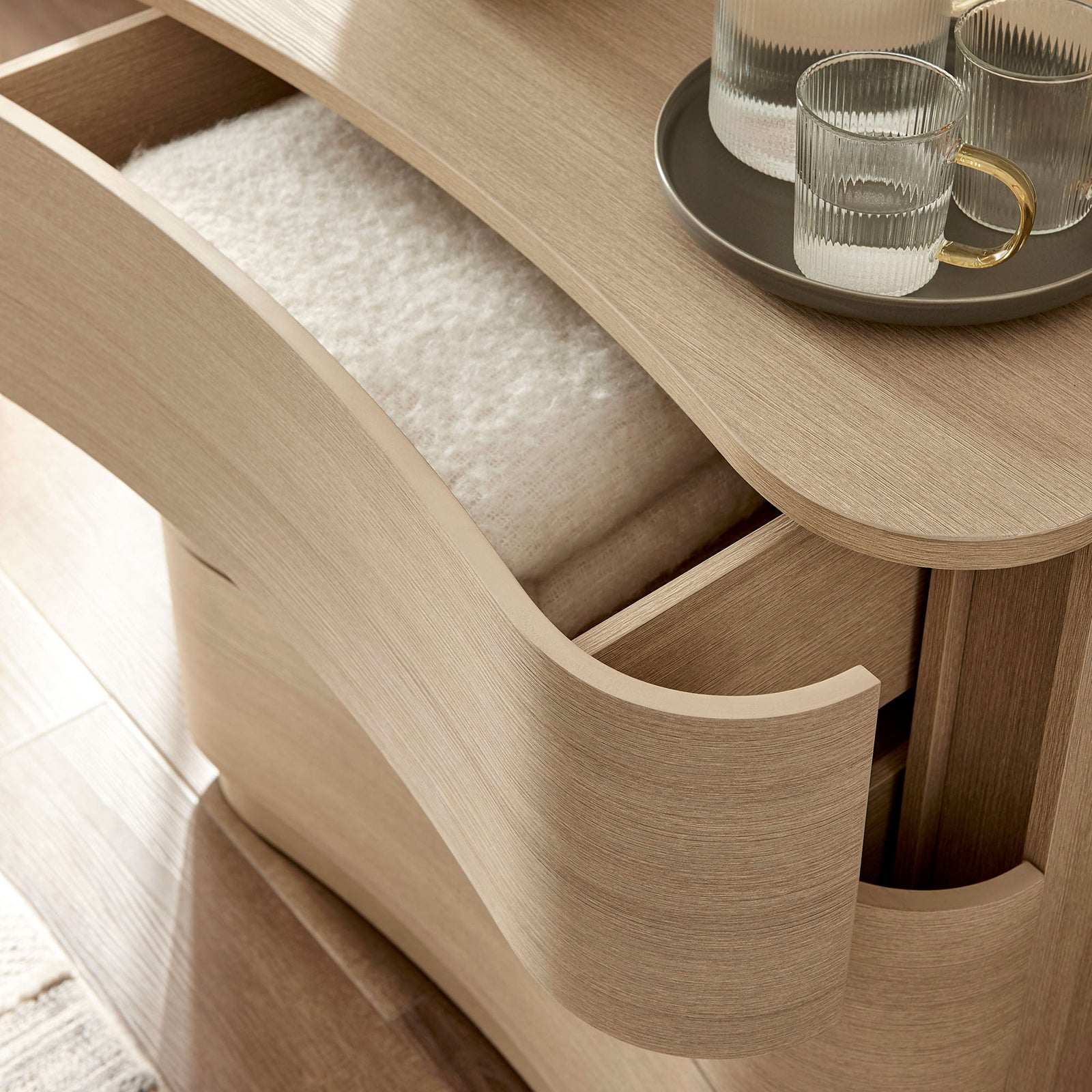 Styled top drawer holds folded textiles and glassware, showcasing everyday storage in a cozy bedroom setting || MOD-7230-BOA || storage_open_room