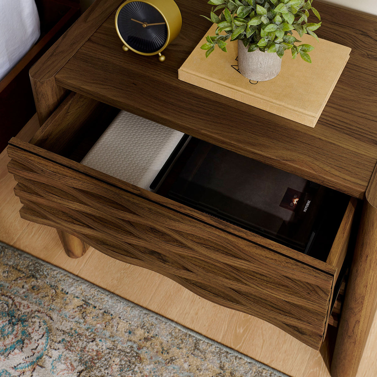 Nightstand styled beside a bed with the top drawer open to display everyday bedside essentials. || MOD-7236-WAL || storage_open_room