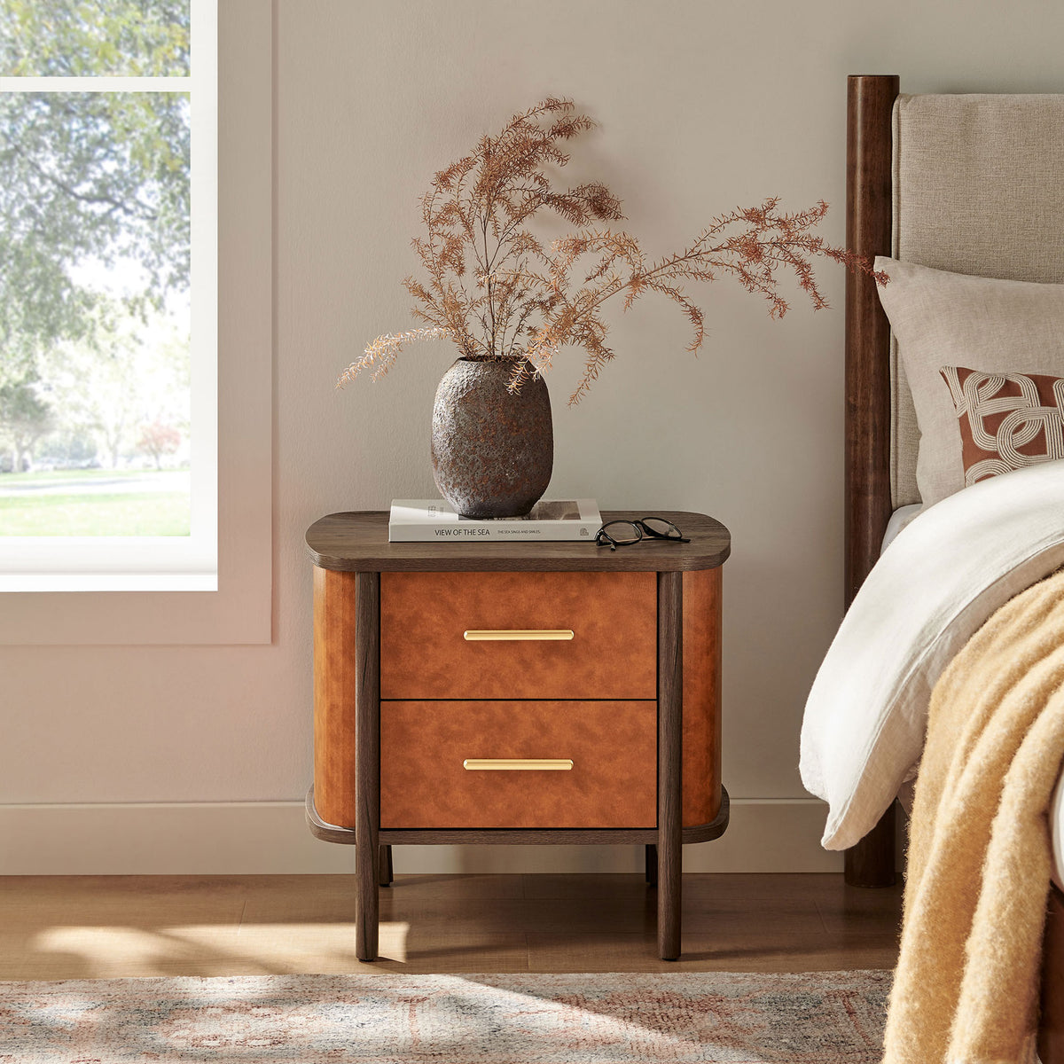Curved vegan leather nightstand beside a bed, styled with decor for a cozy modern bedroom || MOD-7237-WAL-TAN || front_angle_room
