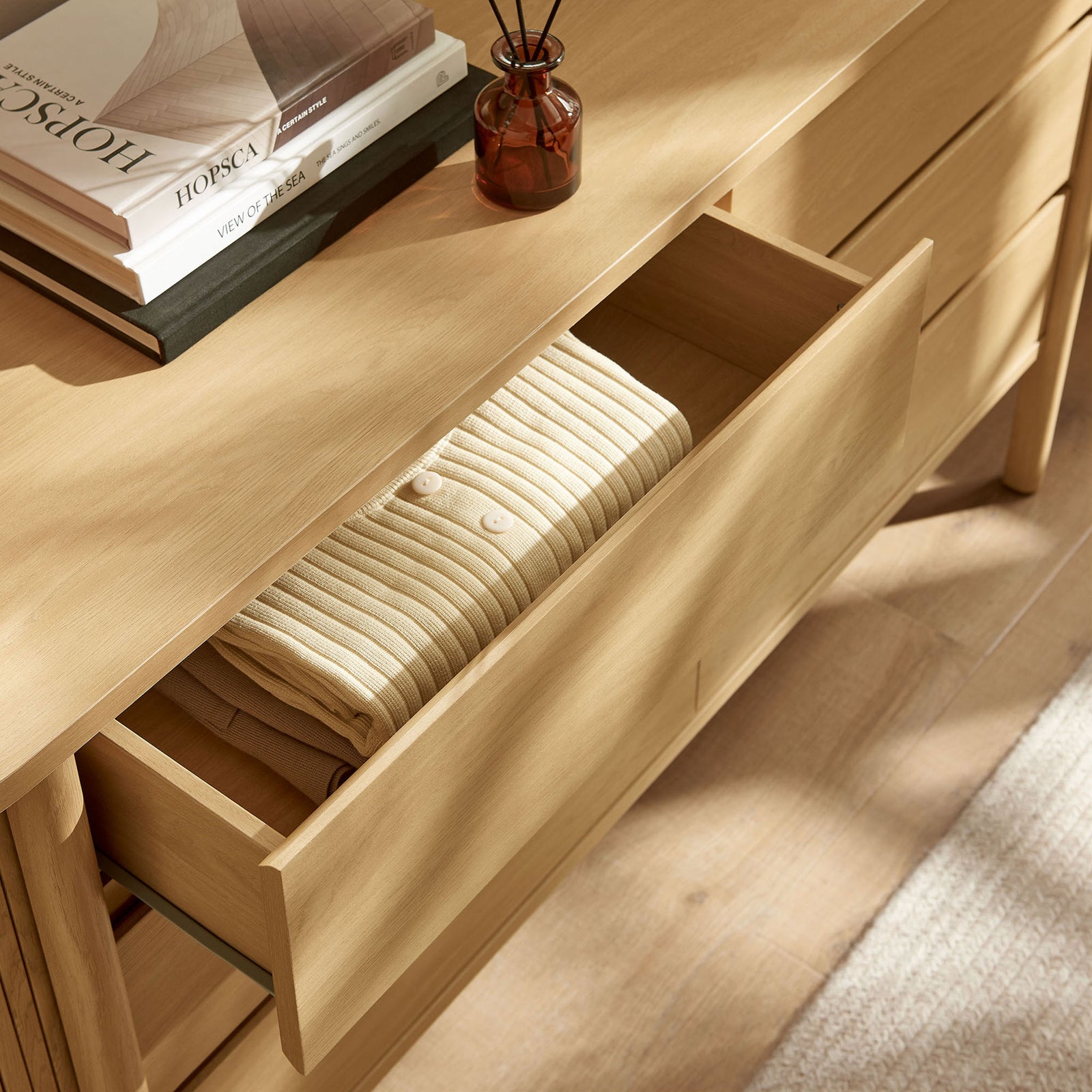 Open dresser drawer in a sunlit room showcasing smooth oak finish and neatly organized clothing storage || MOD-7242-OAK || storage_open_room