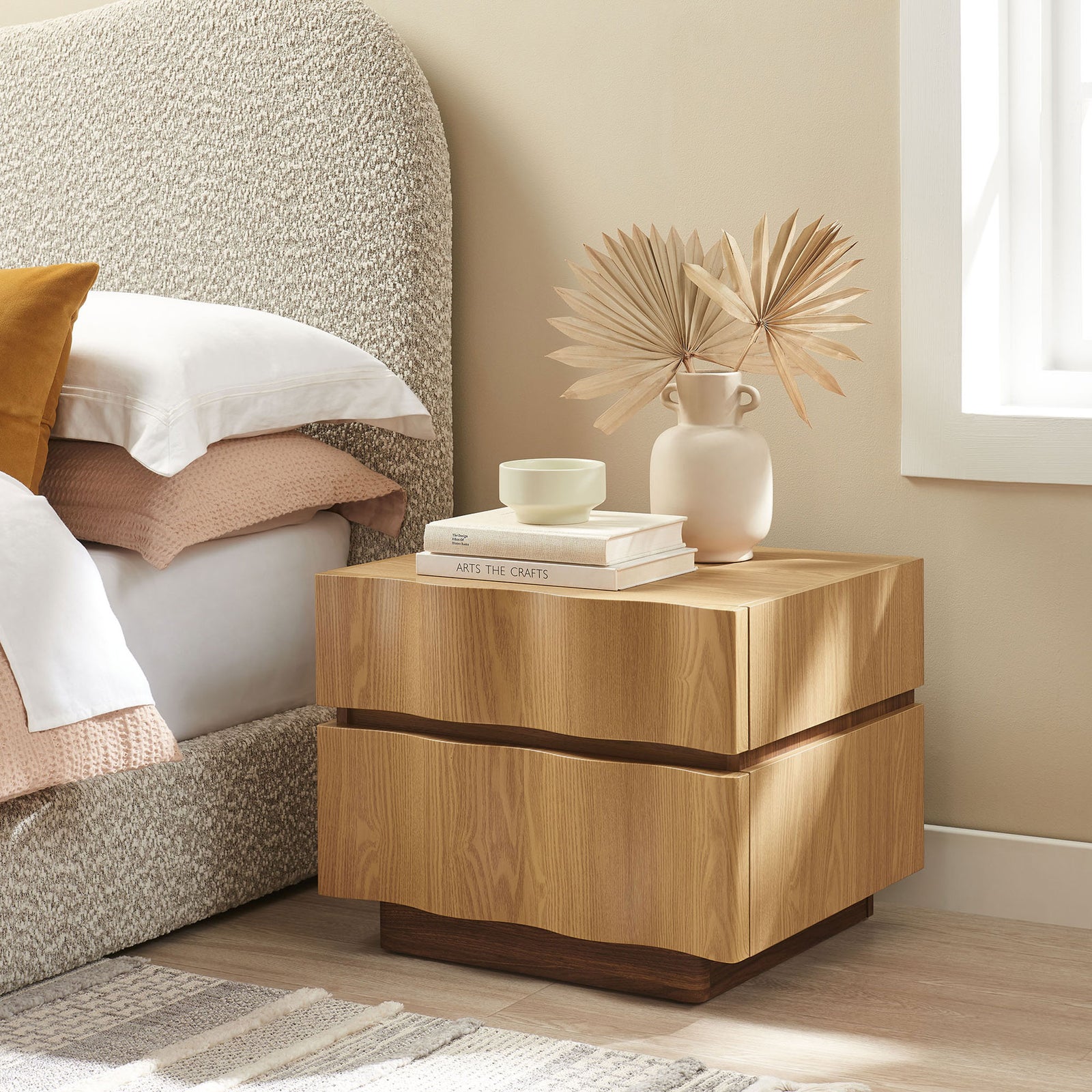 Light oak walnut nightstand styled beside a cozy upholstered bed with decor layered on the tabletop || MOD-7243-LOA-WAL || front_angle_room