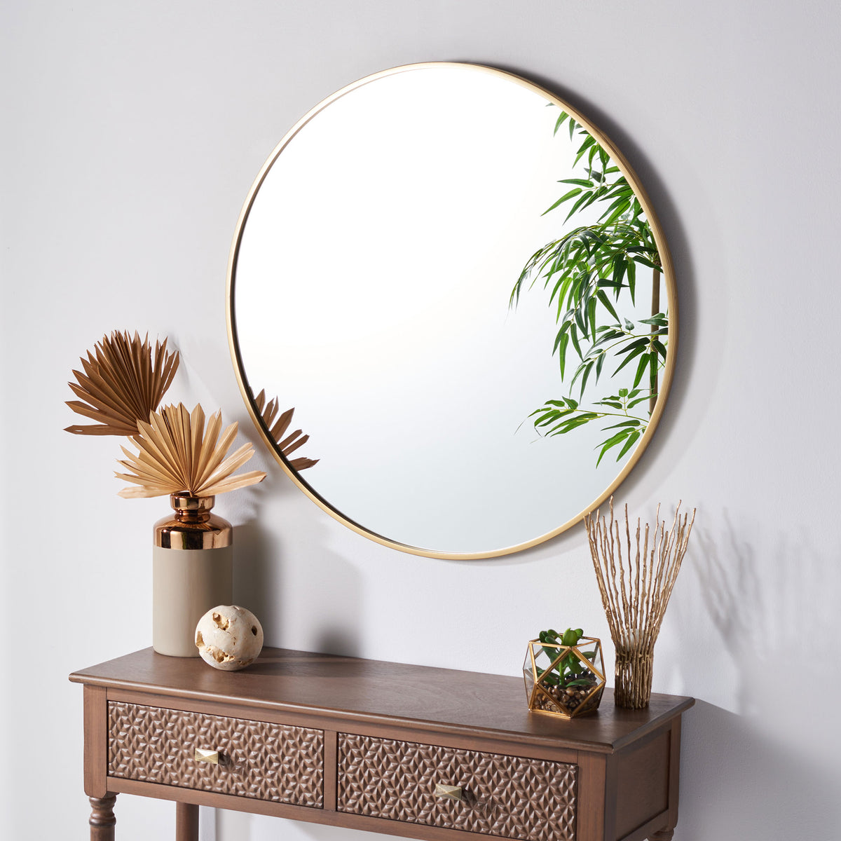 A round, gold-framed mirror brings a warm, airy touch to the wall above a console