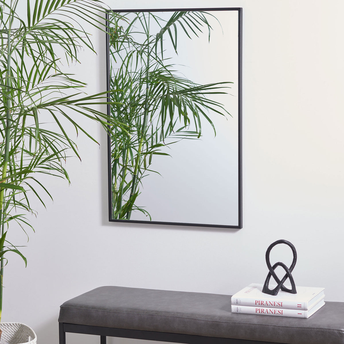 The black-framed rectangular mirror hangs vertically, adding simple elegance above a bench || MRR1061A || front_room