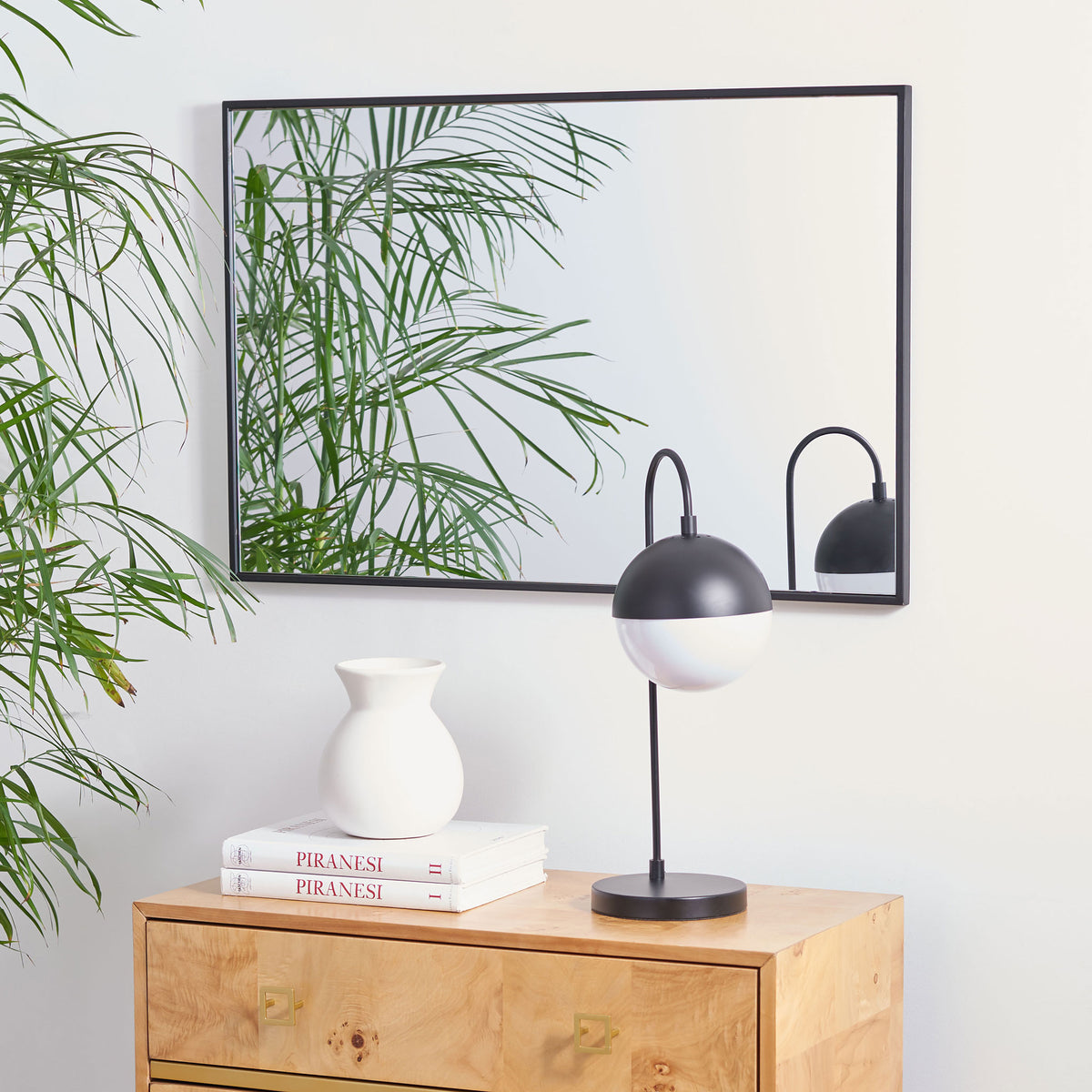 A slim black frame outlines the mirror, hung horizontally above a wood dresser || MRR1061A || front_room