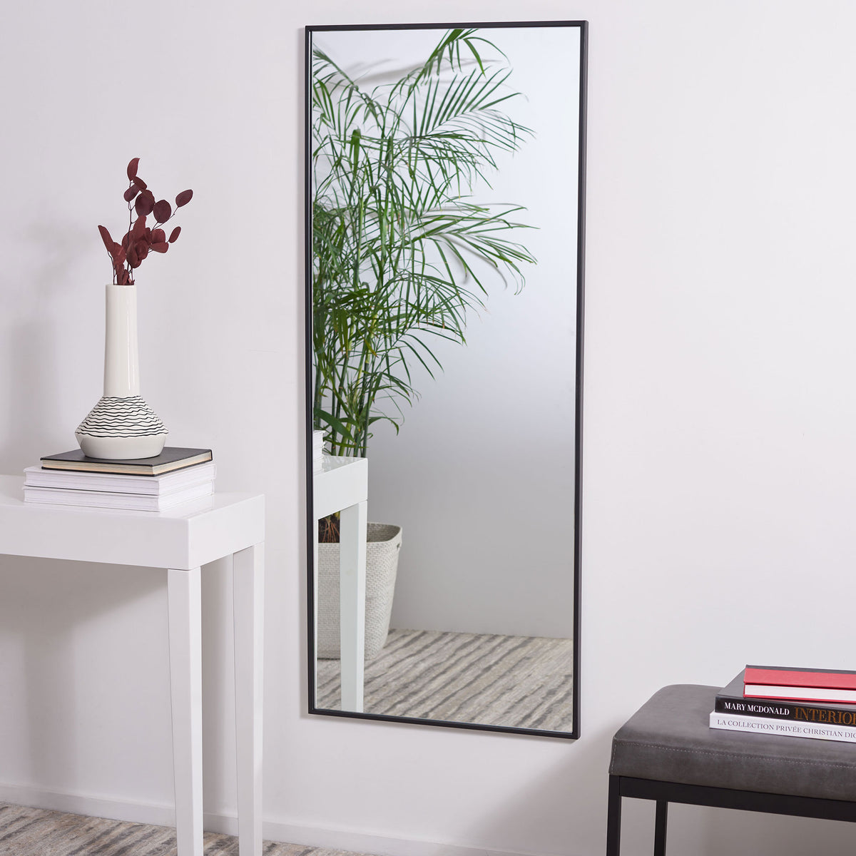 Tall black-framed mirror reflects greenery and adds depth to a bright room || MRR1062A || front_room