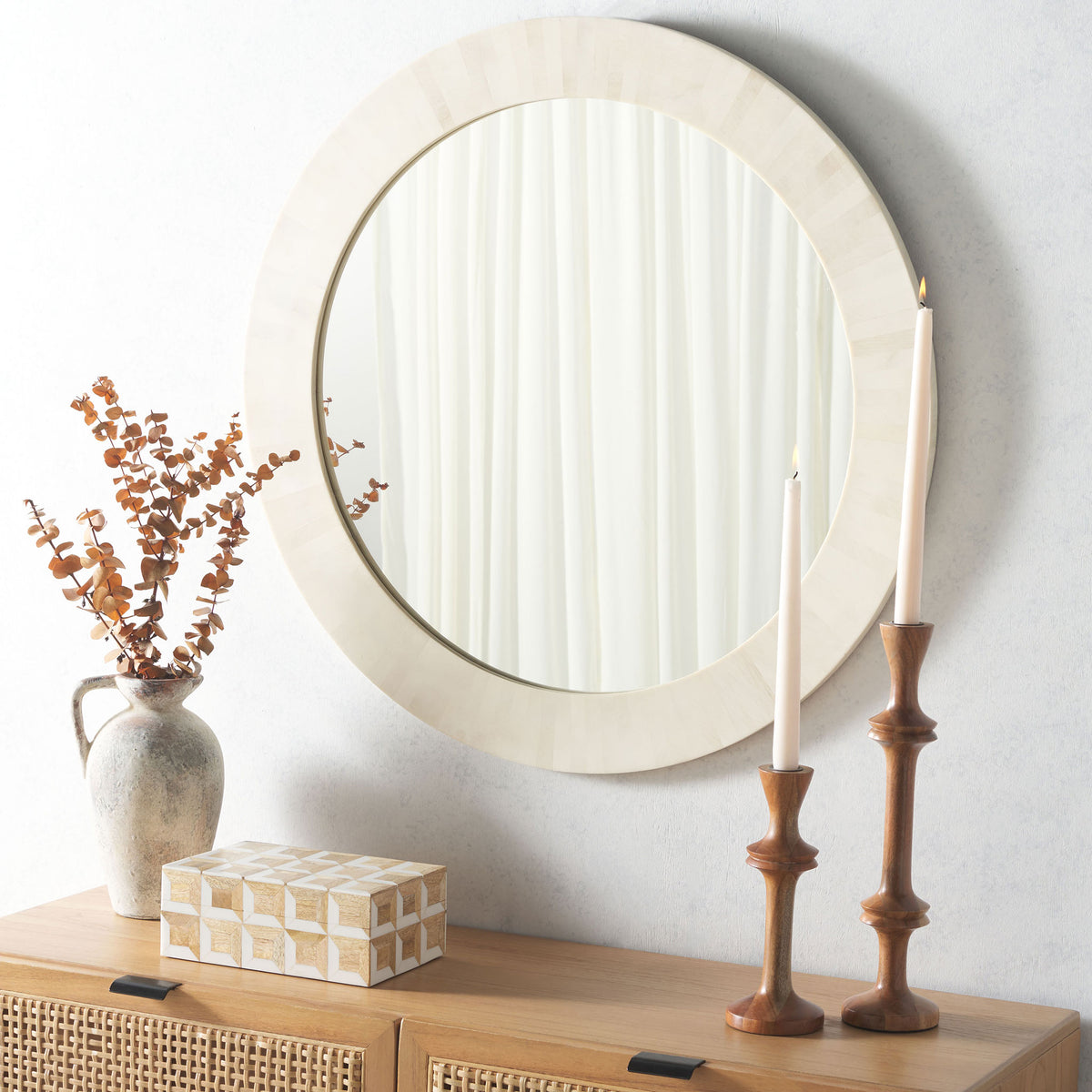 A circular ivory mirror adds reflective light and soft faux-bone texture above a wood console. || MRR1501A || front_room