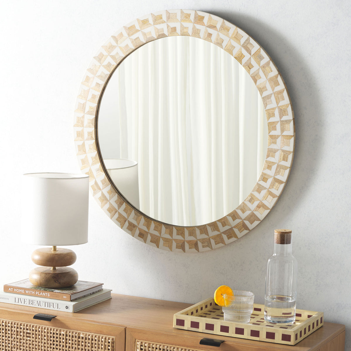 An ivory-and-wood geometric frame adds warmth to a round mirror above a wood console. || MRR1502A || front_room