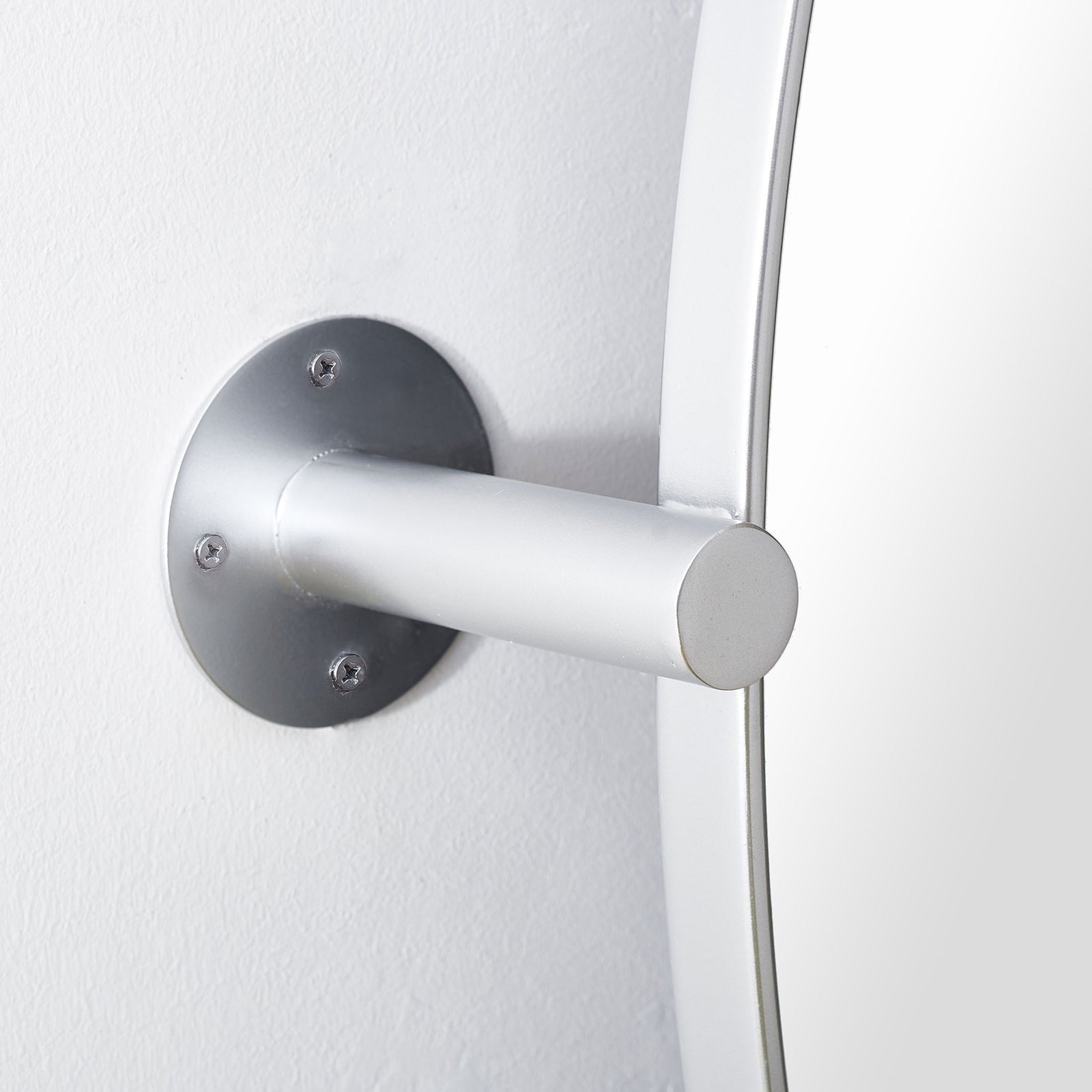A round silver wall plate with visible screws supports the mirror's streamlined metal arm || MRR2000C || detail_room