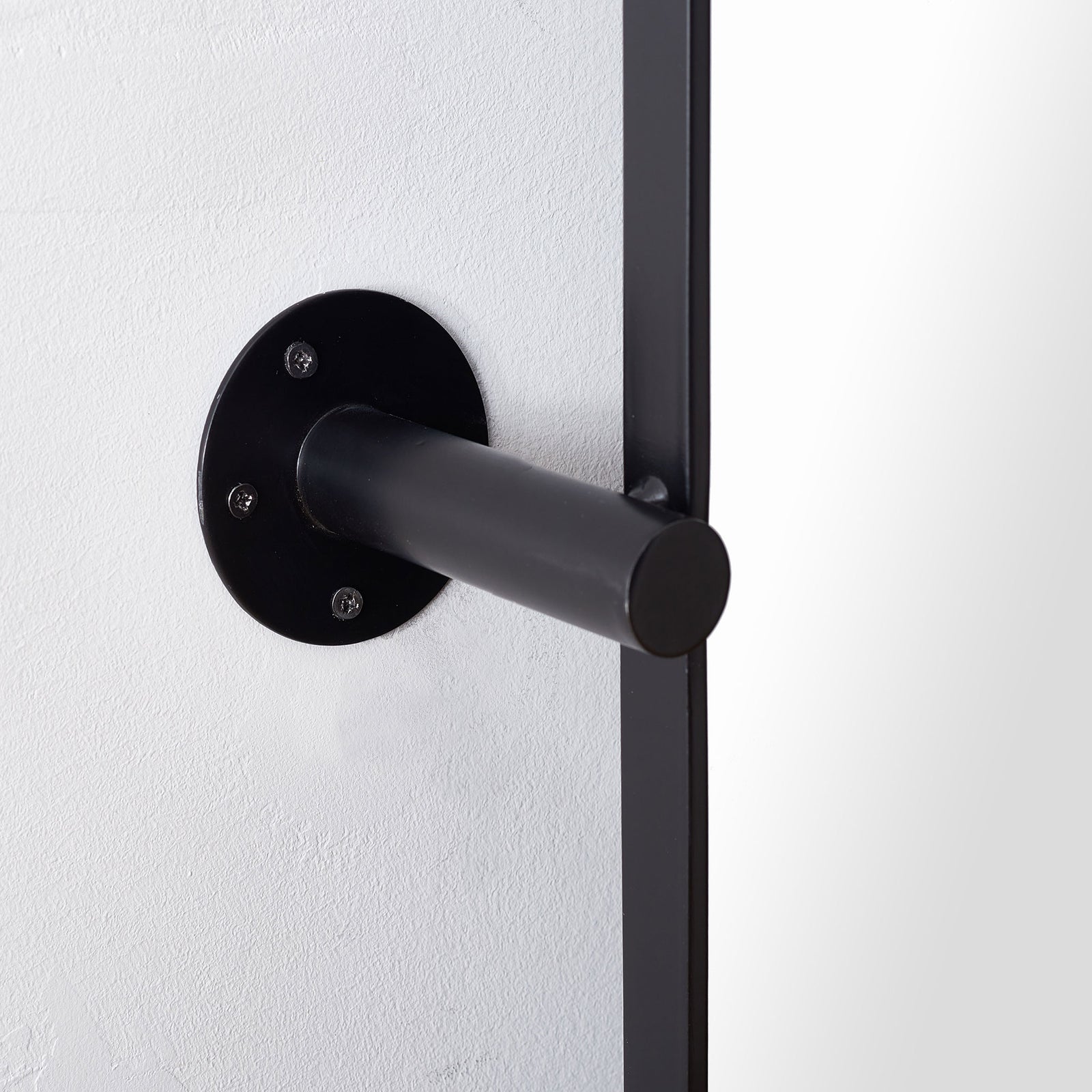 Black tubular support extends from a round, screw-mounted wall plate beside the mirror frame. || MRR2001A || detail_room