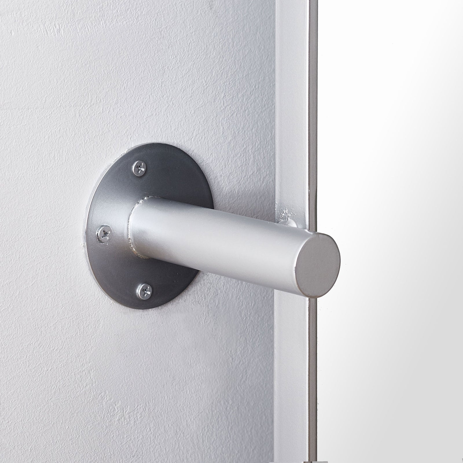 Silver tubular arm and circular wall plate support the mirror beside its narrow metal frame. || MRR2001B || detail_room