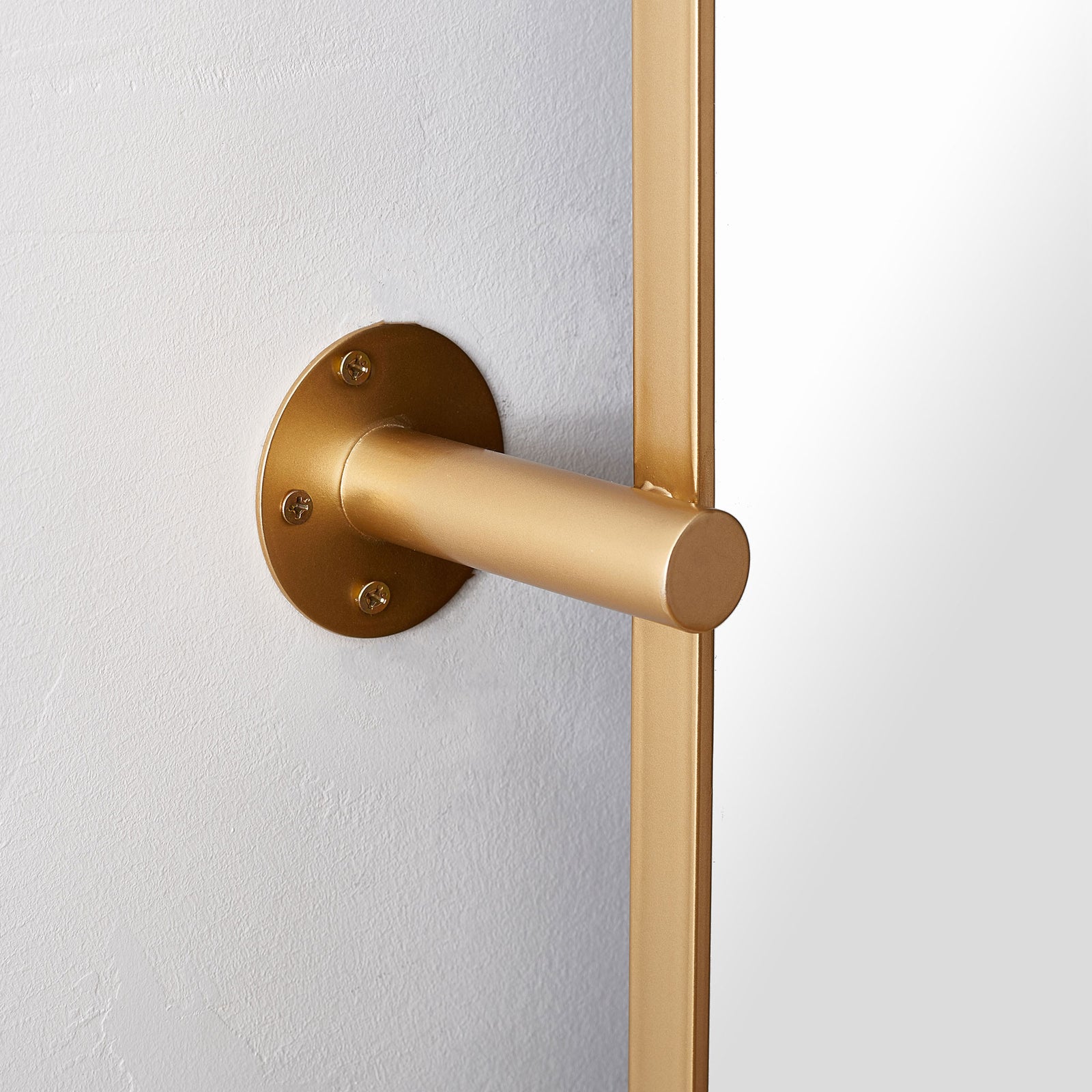 Brass-finished cylindrical mount and round wall plate support the mirror beside its slender frame. || MRR2001C || detail_room