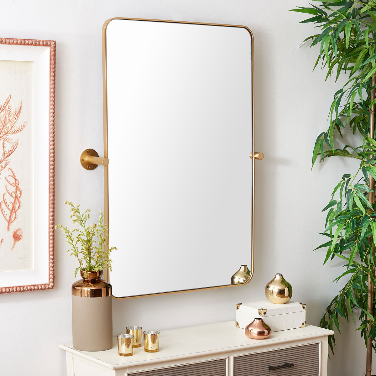 Rounded brass-framed mirror adds warmth above a white console with metallic accessories. || MRR2001C || front_angle_room