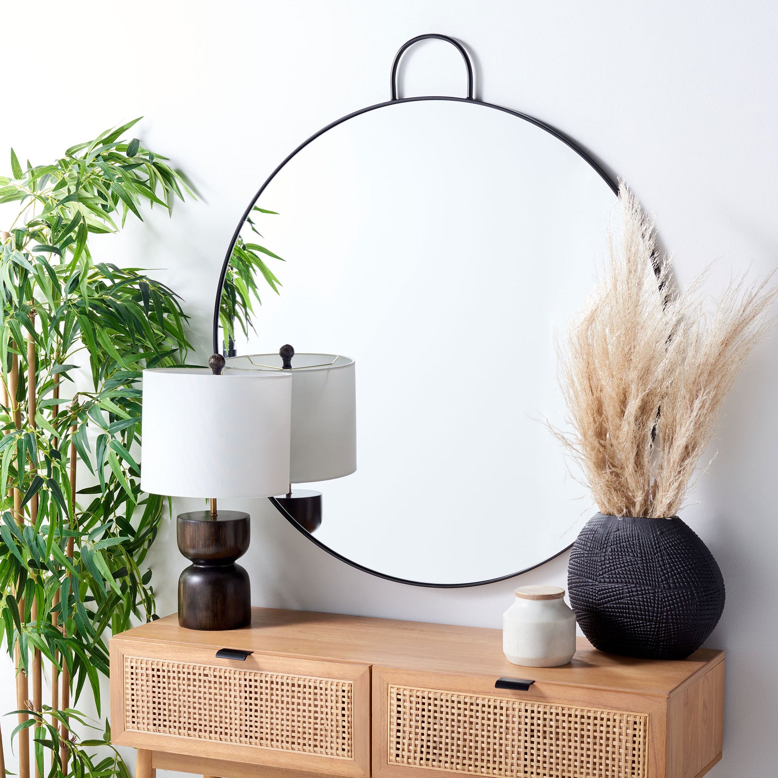 A round black-framed mirror brings modern depth above a woven-front console || MRR2002A || front_angle_room