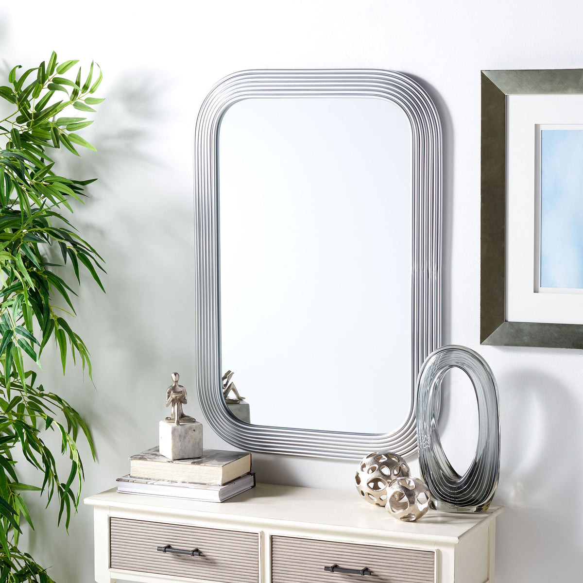 Silver ribbed mirror brightens the wall above a console with textured drawers