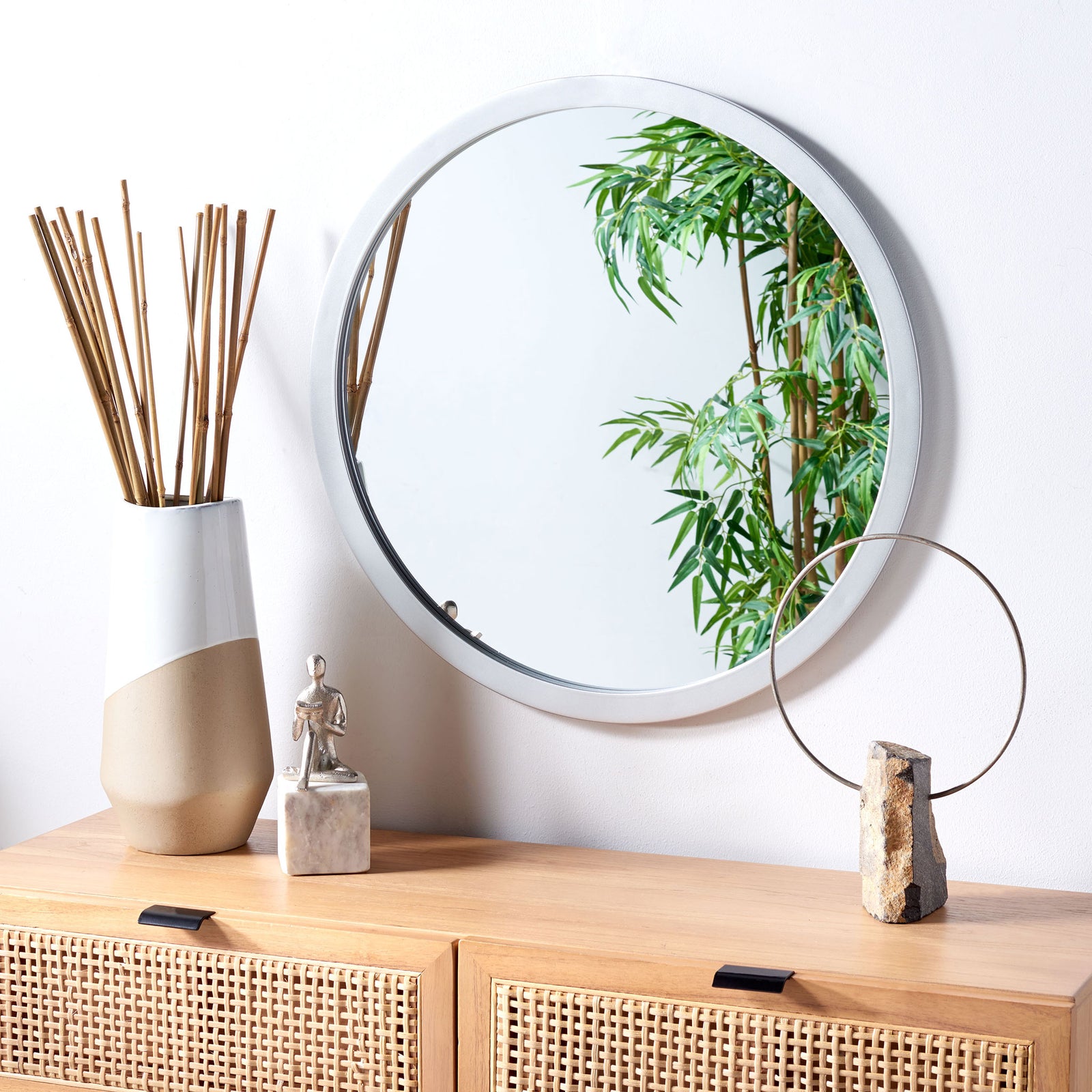 A silver-framed round mirror brings an airy glow above a woven-front wood cabinet || MRR2006D || front_angle_room