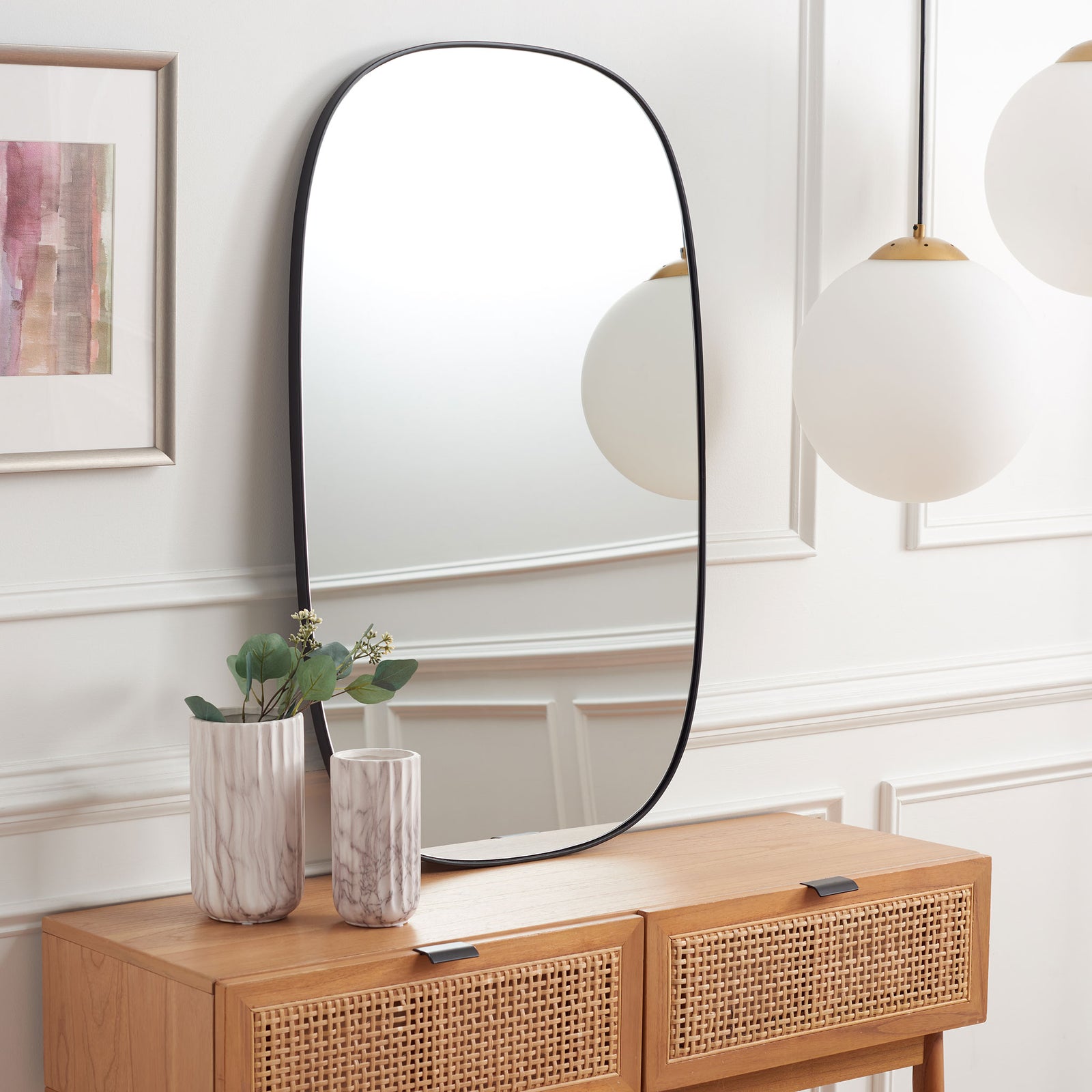 Soft curves and a slim black frame bring modern elegance above a wood console || MRR2007B || front_angle_room