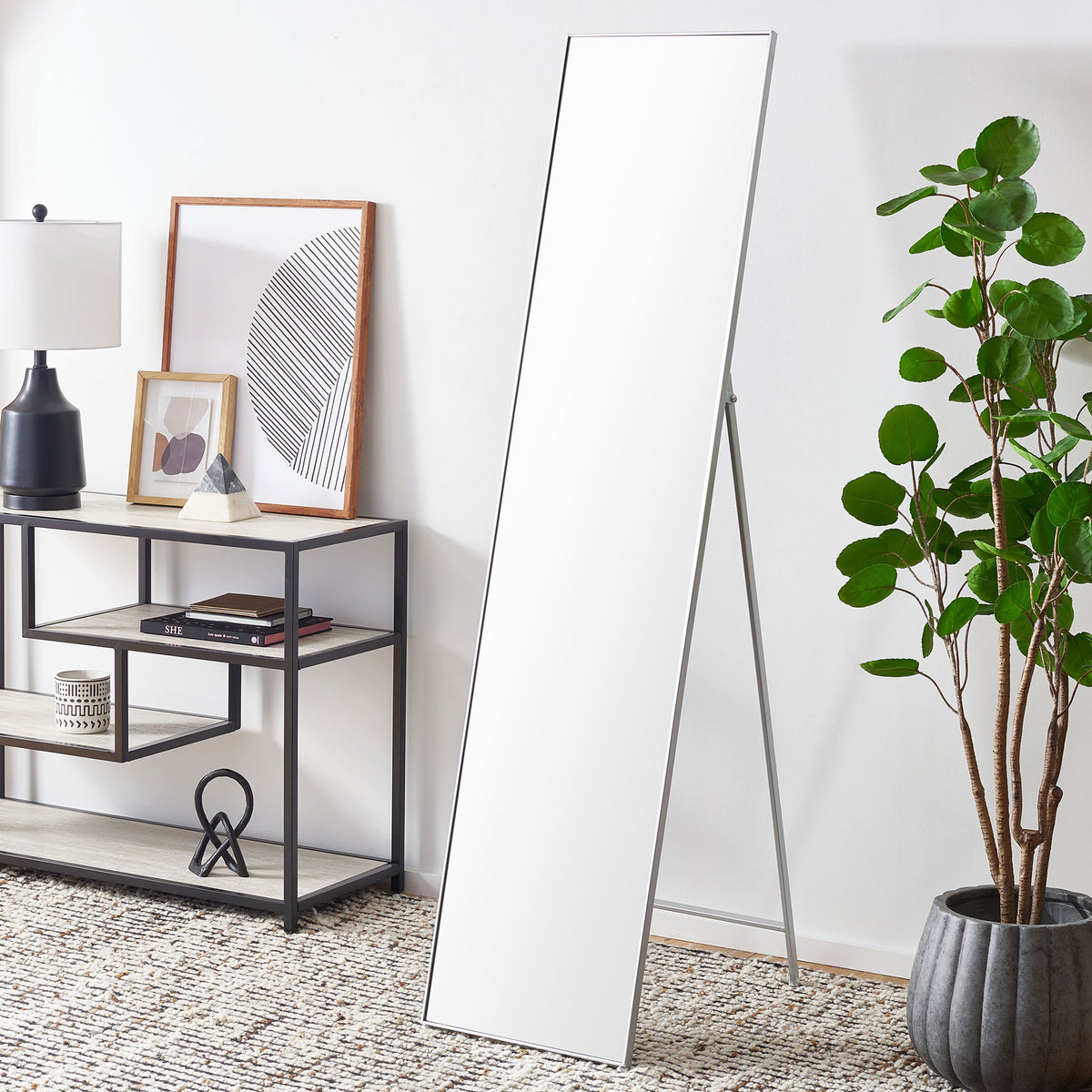 A slim silver-framed floor mirror stands beside contemporary furniture, brightening the space || MRR2008B || front_angle_room