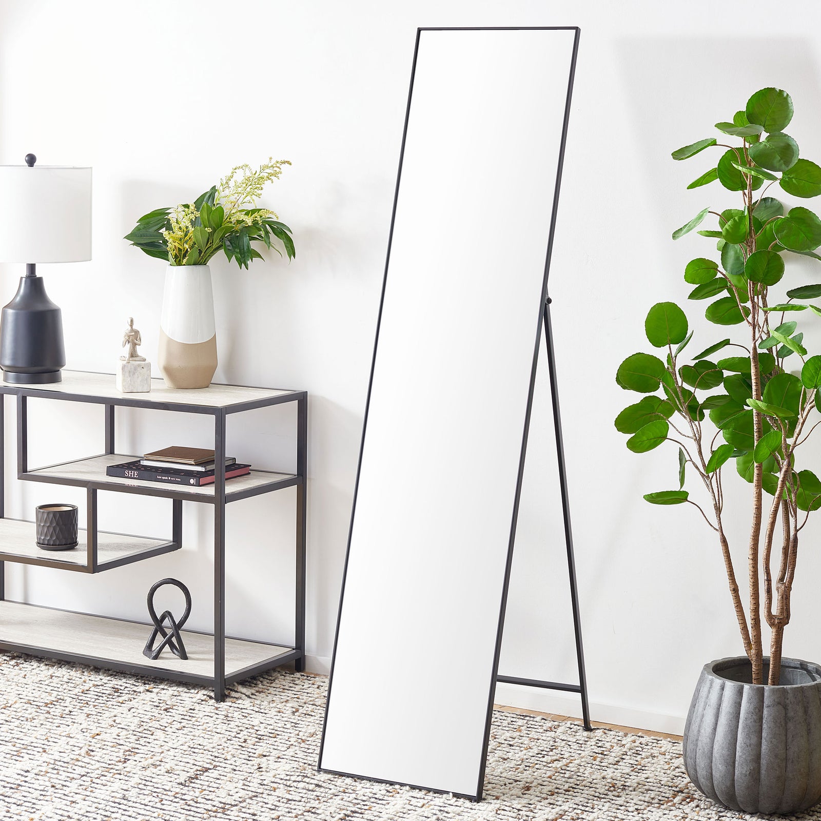 A full-length mirror with a slim black frame and rear support adds modern simplicity to a living space || MRR2008C || front_angle_room