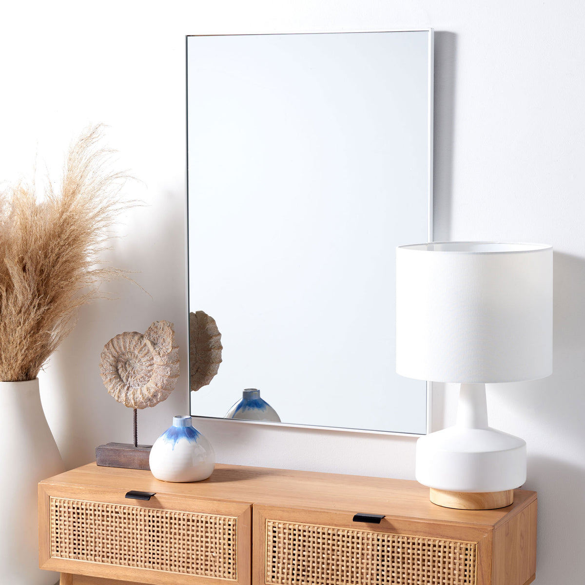 A white-framed wall mirror lends clean lines and an airy feel above a wood cabinet.
