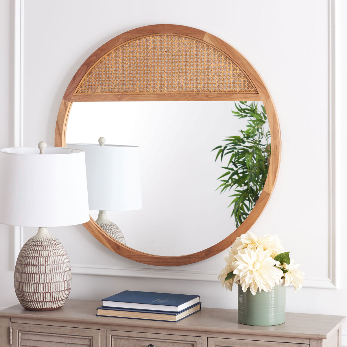 Natural wood frames a round mirror with a woven cane upper panel above a console