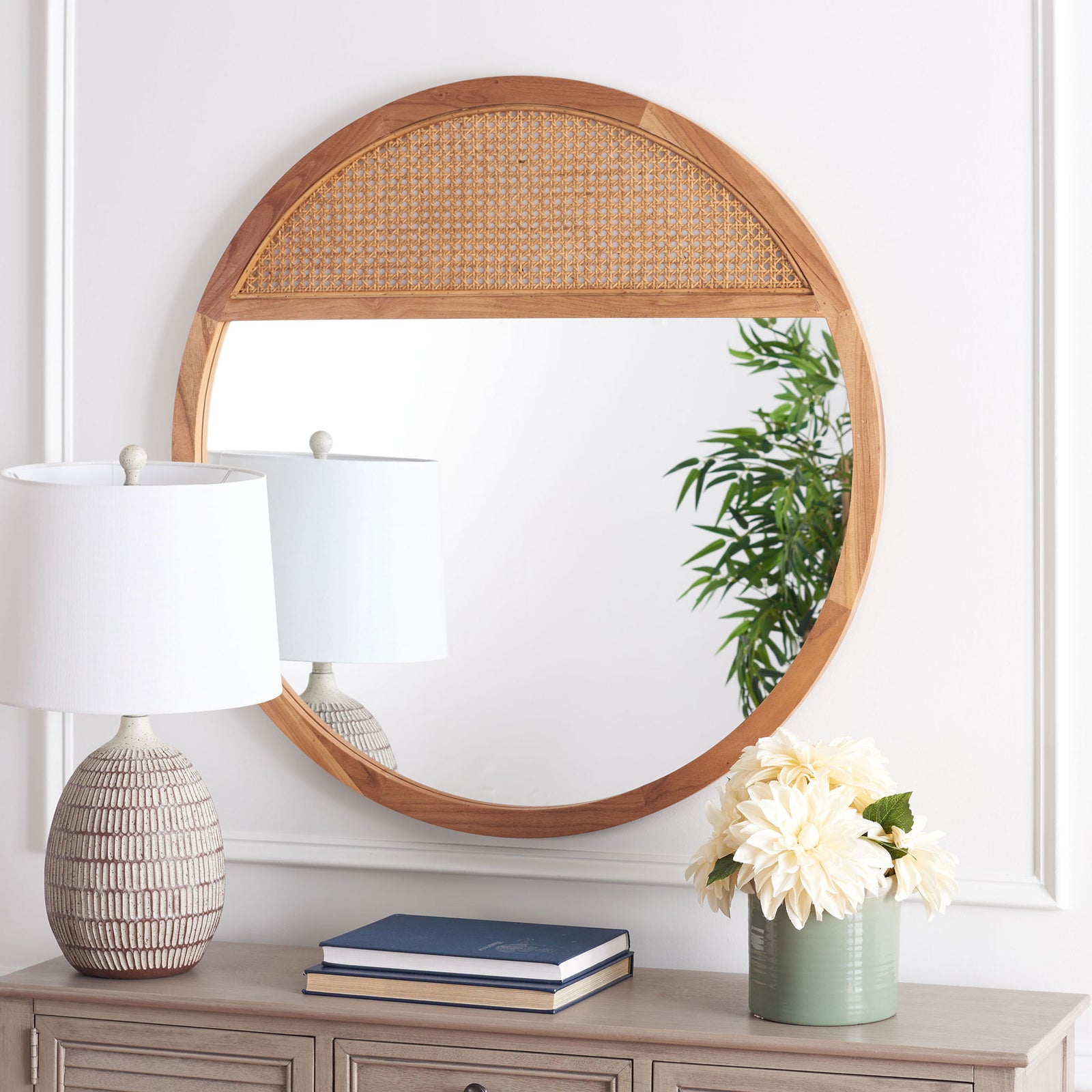 Natural wood frames a round mirror with a woven cane upper panel above a console || MRR2013B || front_room