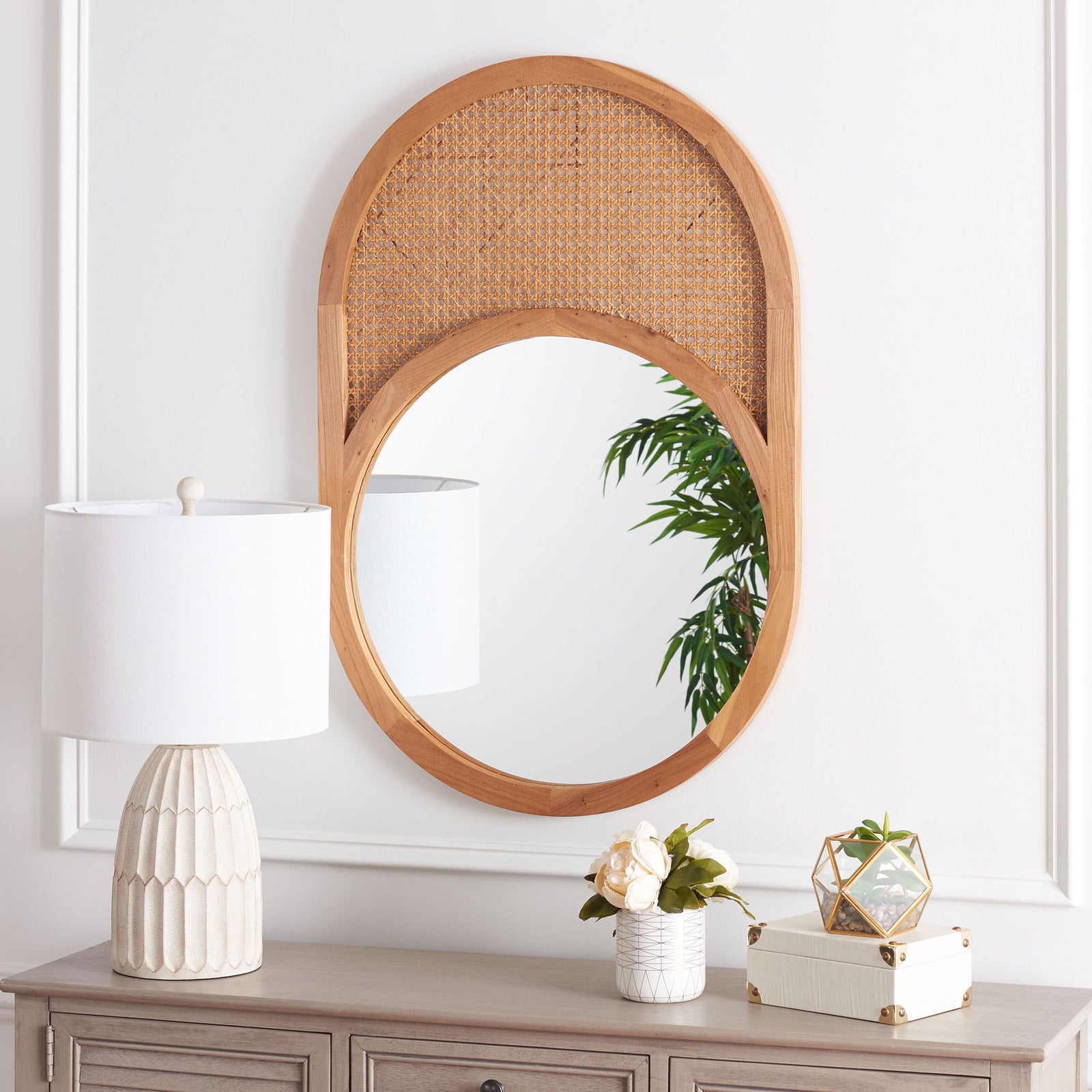 An oval natural wood mirror with woven cane above the glass lends warmth to a console display. || MRR2019B || front_room