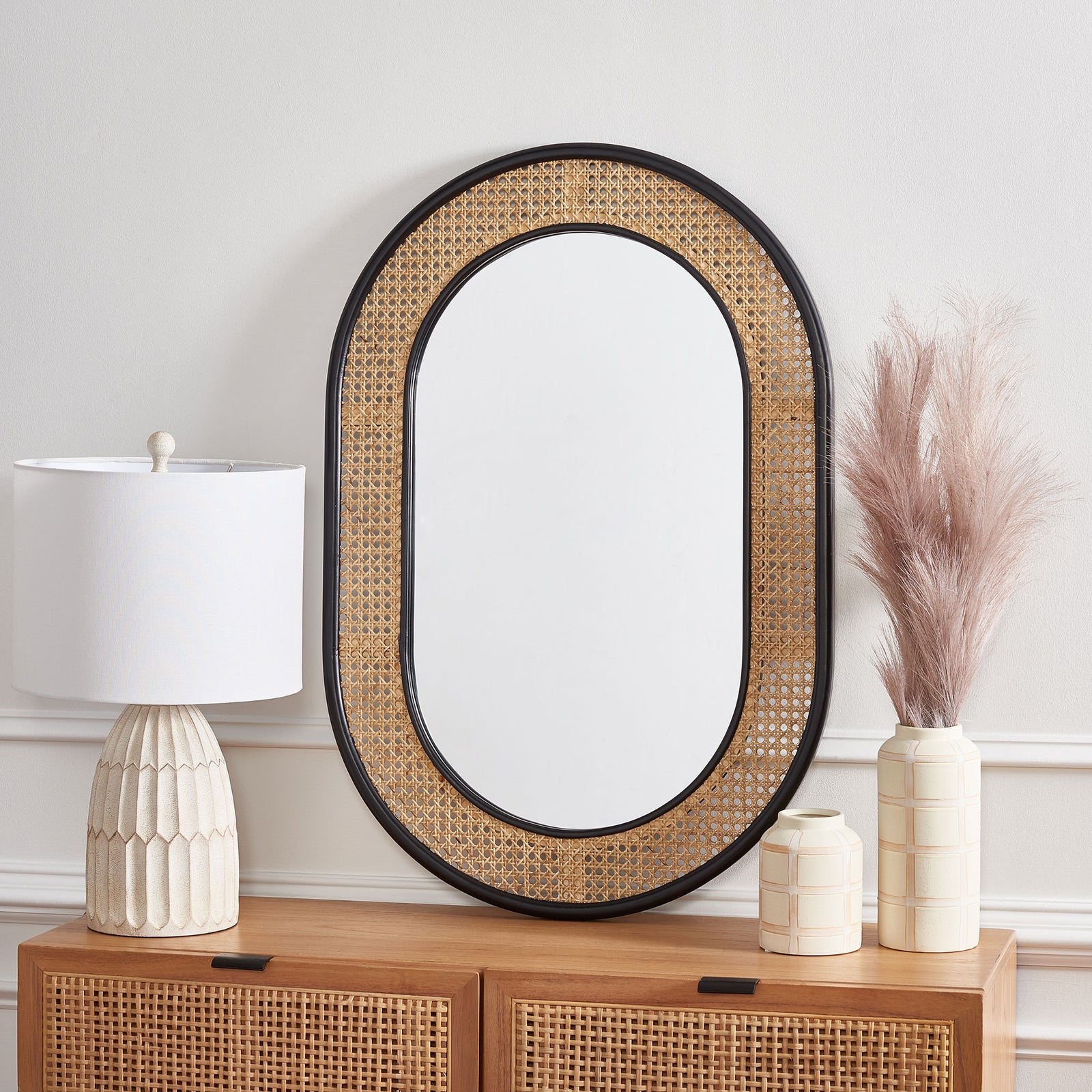 Black-framed capsule mirror adds natural woven texture atop a wood cabinet || MRR2020A || front_room