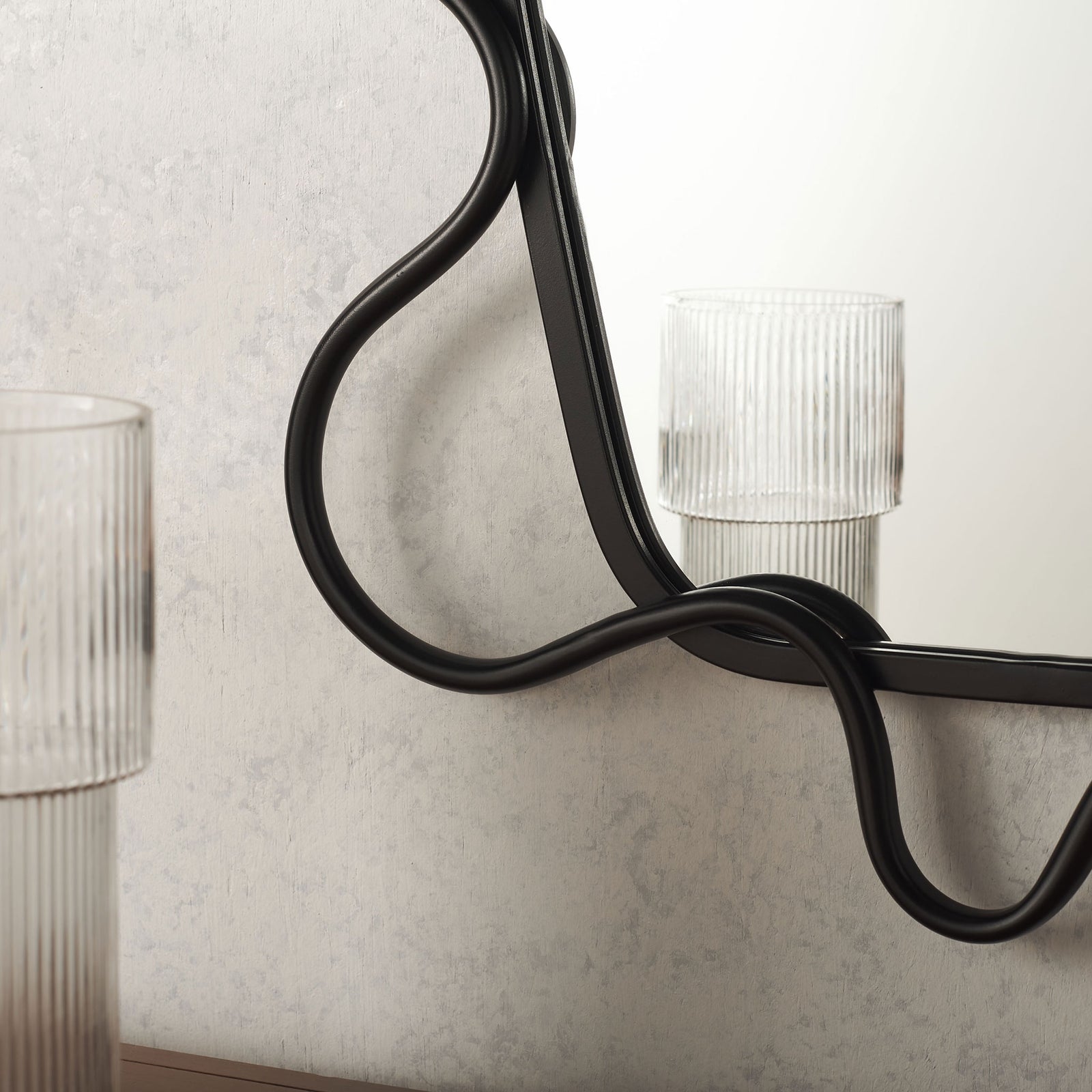 Black metal tubing curves around the mirror edge with an airy, flowing silhouette || MRR2500A || detail_room