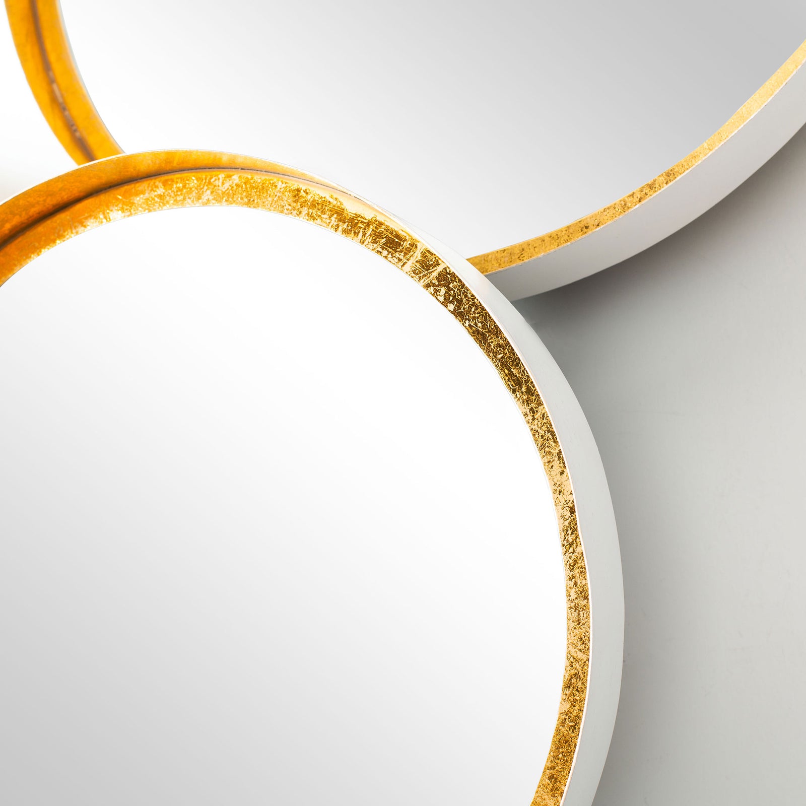 Gold foil edges and smooth white sides define the junction of two circular mirrors. || MRR3002B || detail_studio