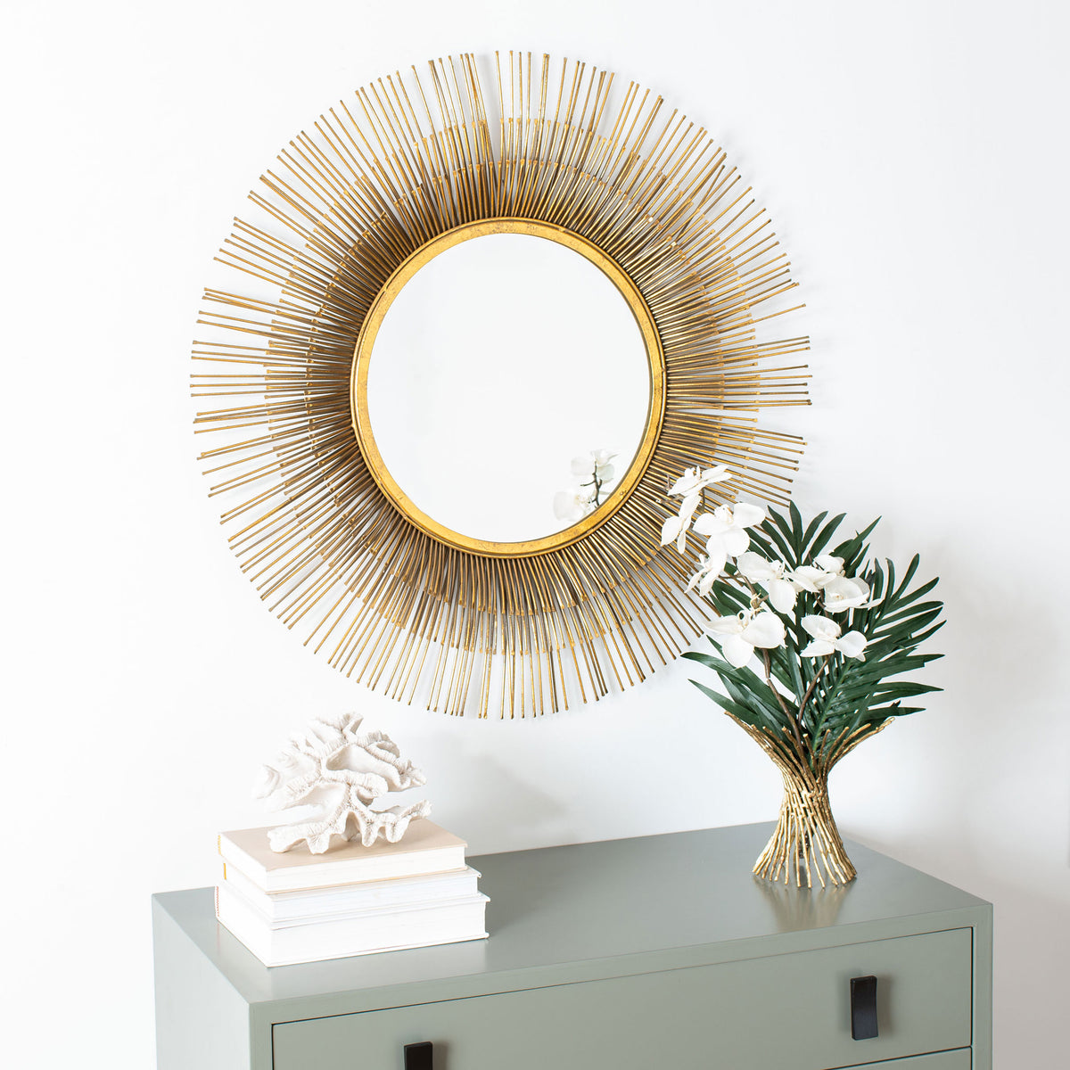 Radiating gold rays make this round wall mirror a sculptural focal point above a cabinet.