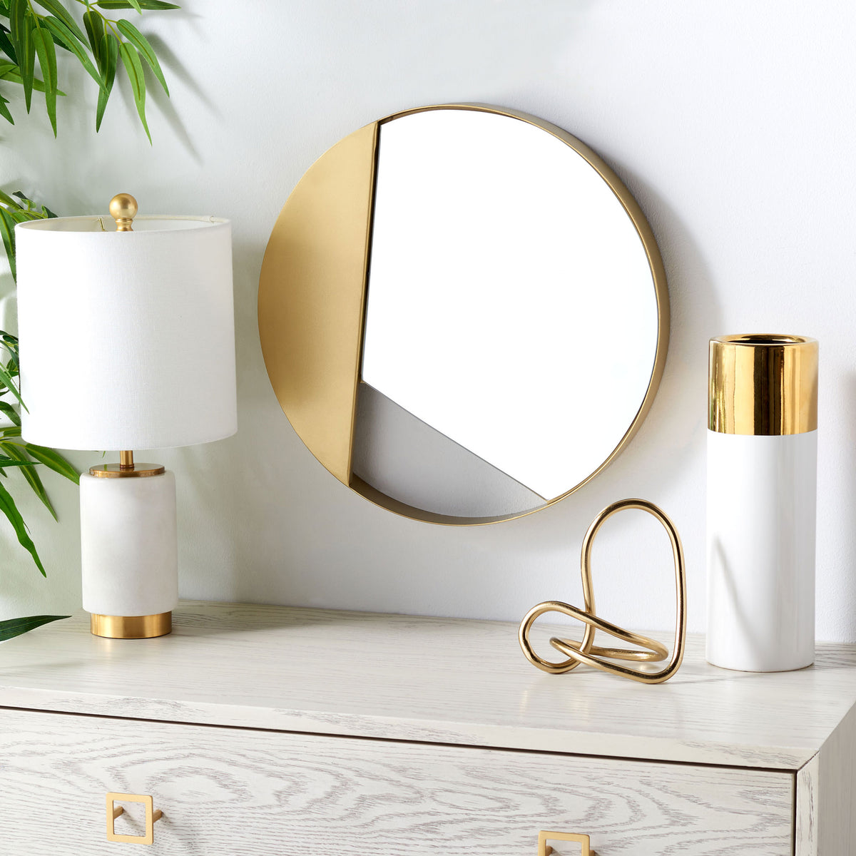 A brass-accented round mirror adds warmth above a light wood dresser.